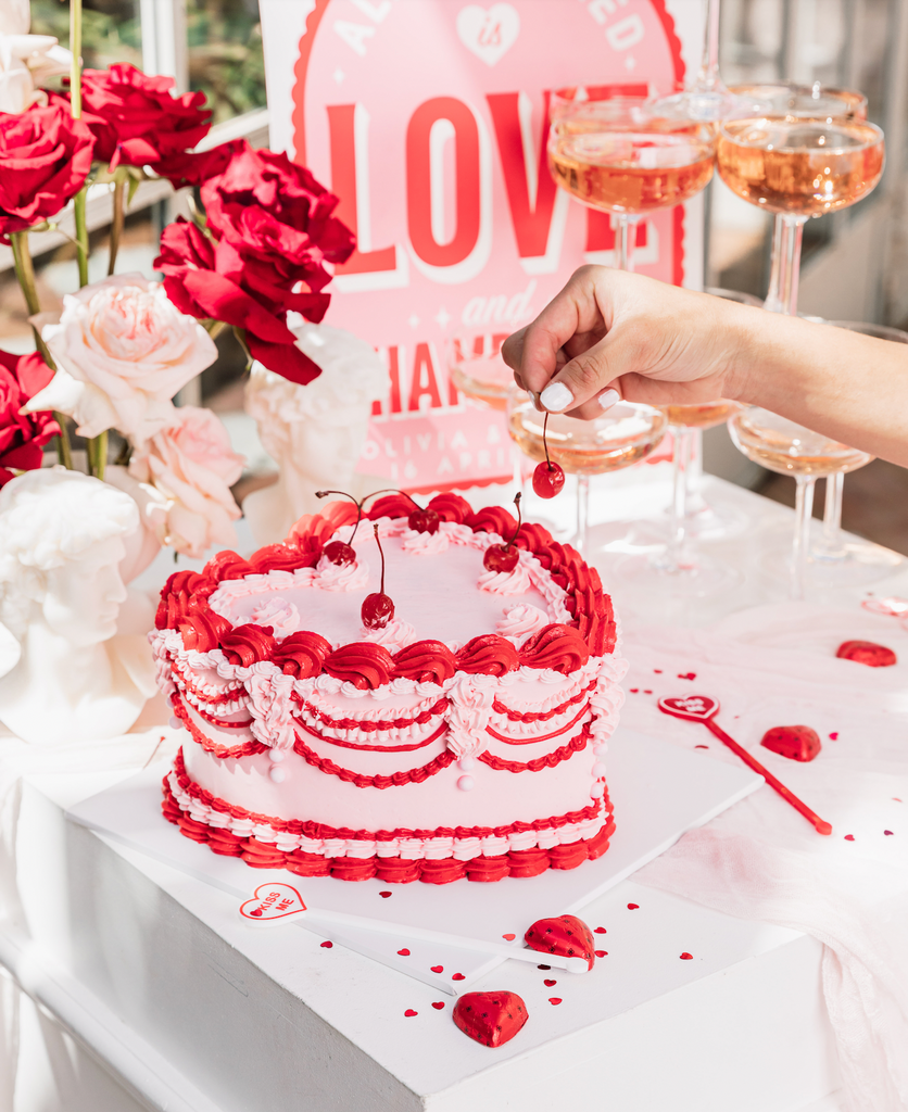 Bride takes cherry from red and pink heart shaped vintage cake