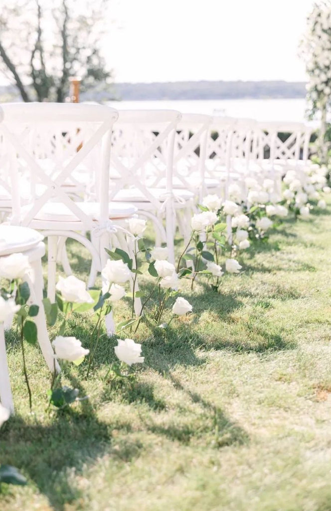 White long stem roses line the walkway of the aisle for a garden wedding ceremony with with chairs 