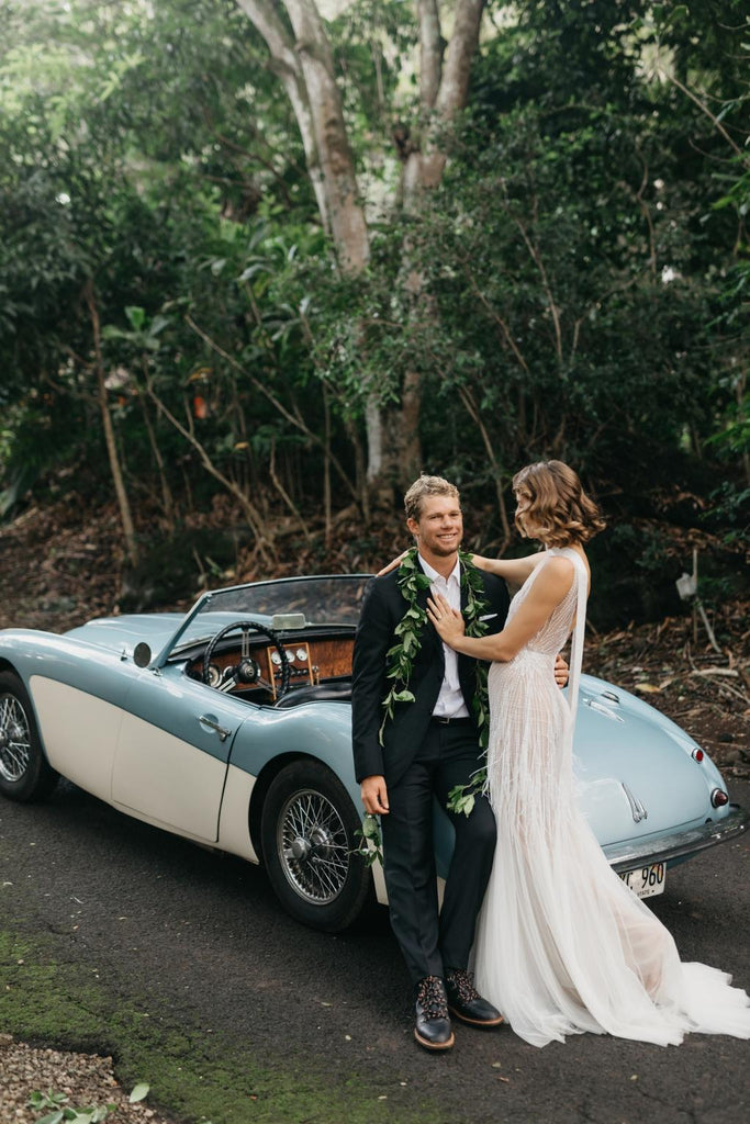 Bride and Groom pose in front of blue vintage car 