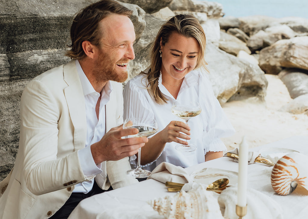 Bride and groom drink champagne at their seaside elopement 