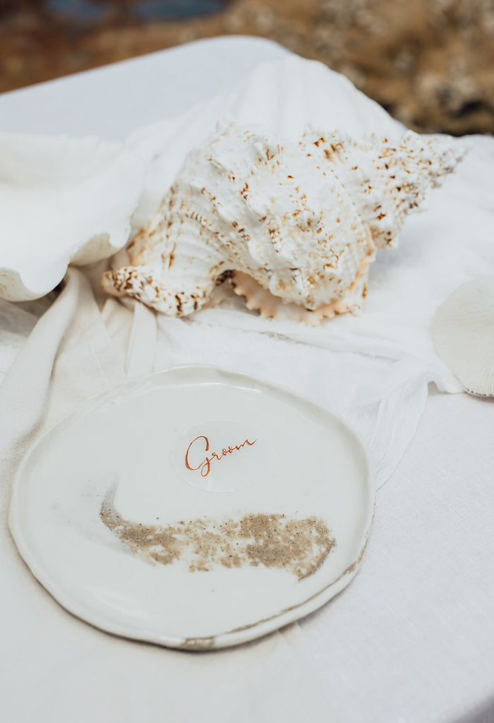 Groom shell place card sits on plate next to shell