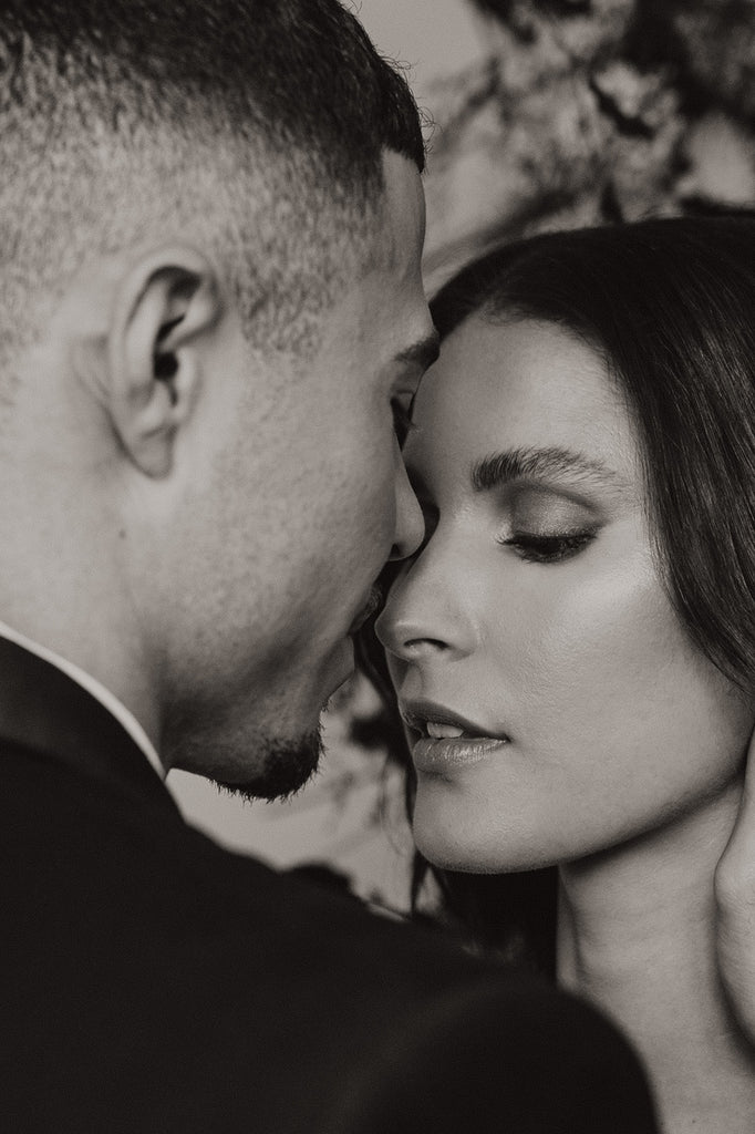 black and white image of bride and groom holding their heads together 