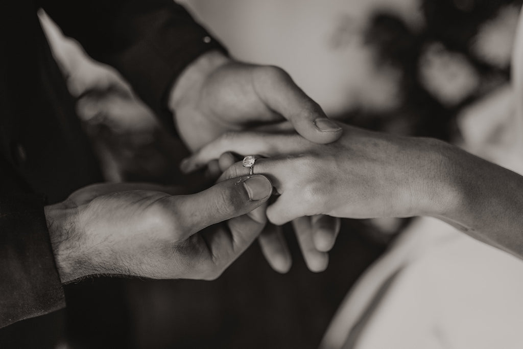 Groom slides wedding ring on brides finger