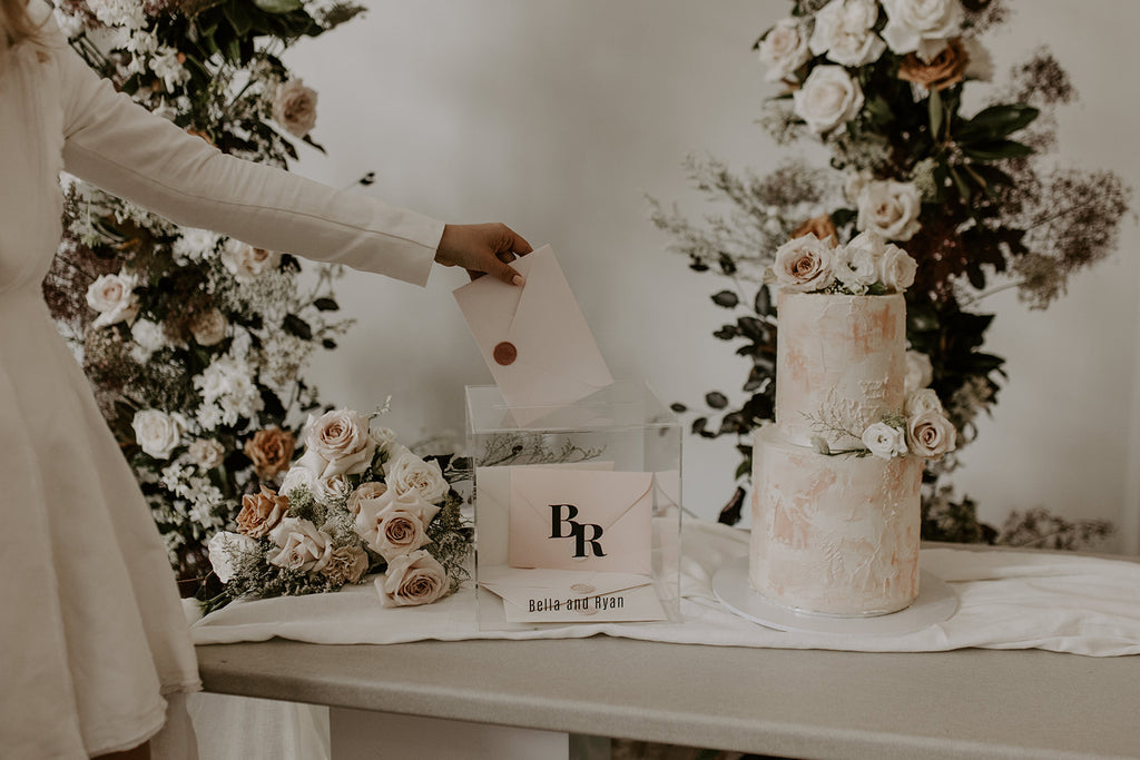 guest puts card in wishing well that sits next to two tier wedding cake