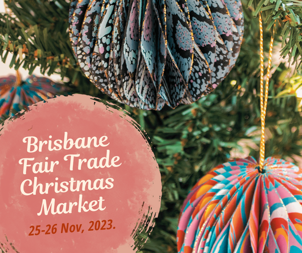 Brisbane Fair Trade Christmas Market 25 - 26 November 2023. Background depicts up close multi coloured paper Christmas baubles on a Christmas tree.