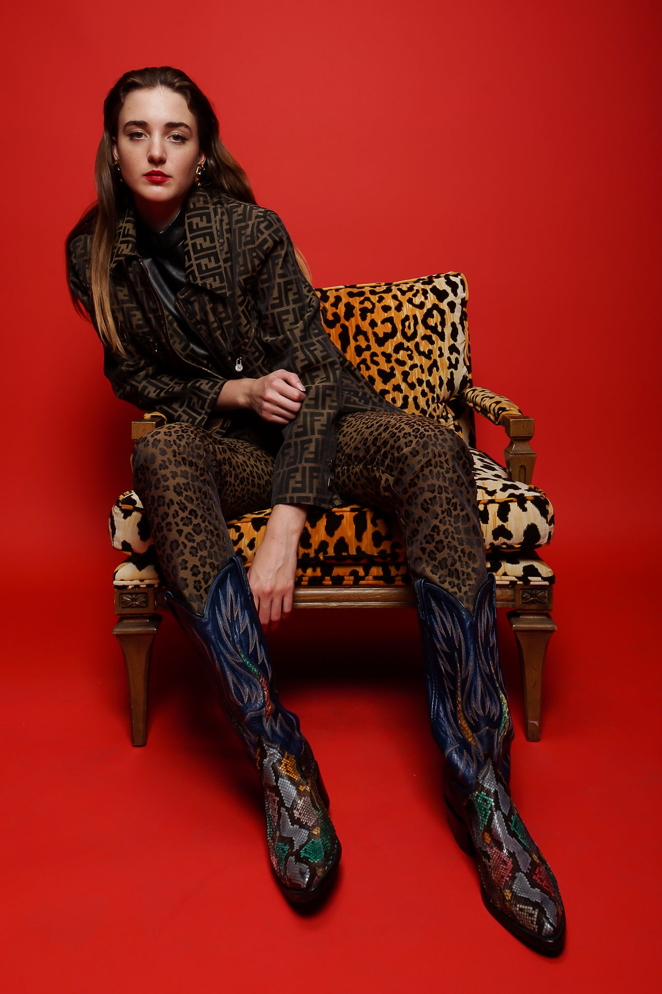 Girl in Fendi Zucca twill zip jacket & animal pant in animal chair on red at Recess Los Angeles