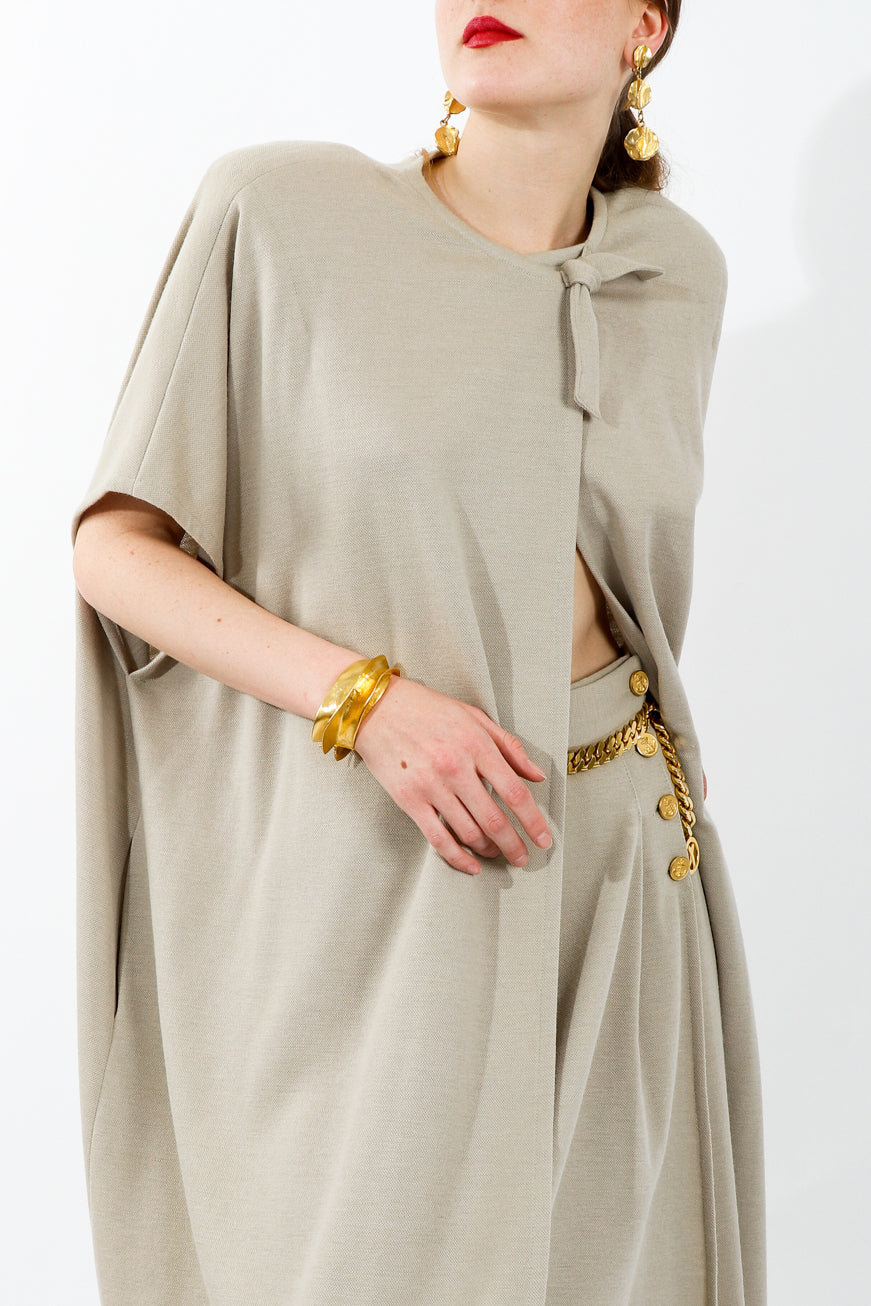 Girl wearing beige Sonia Rykiel cape and shorts set with gold earrings bracelet and belt