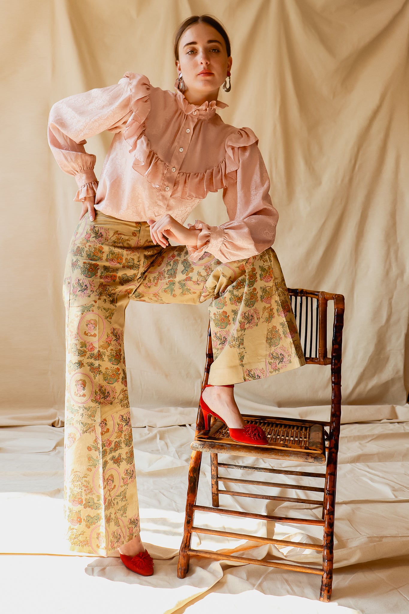 Recess Vintage Consignment LA Girl stepping on chair in YSL Blouse & Painted Suede Pants