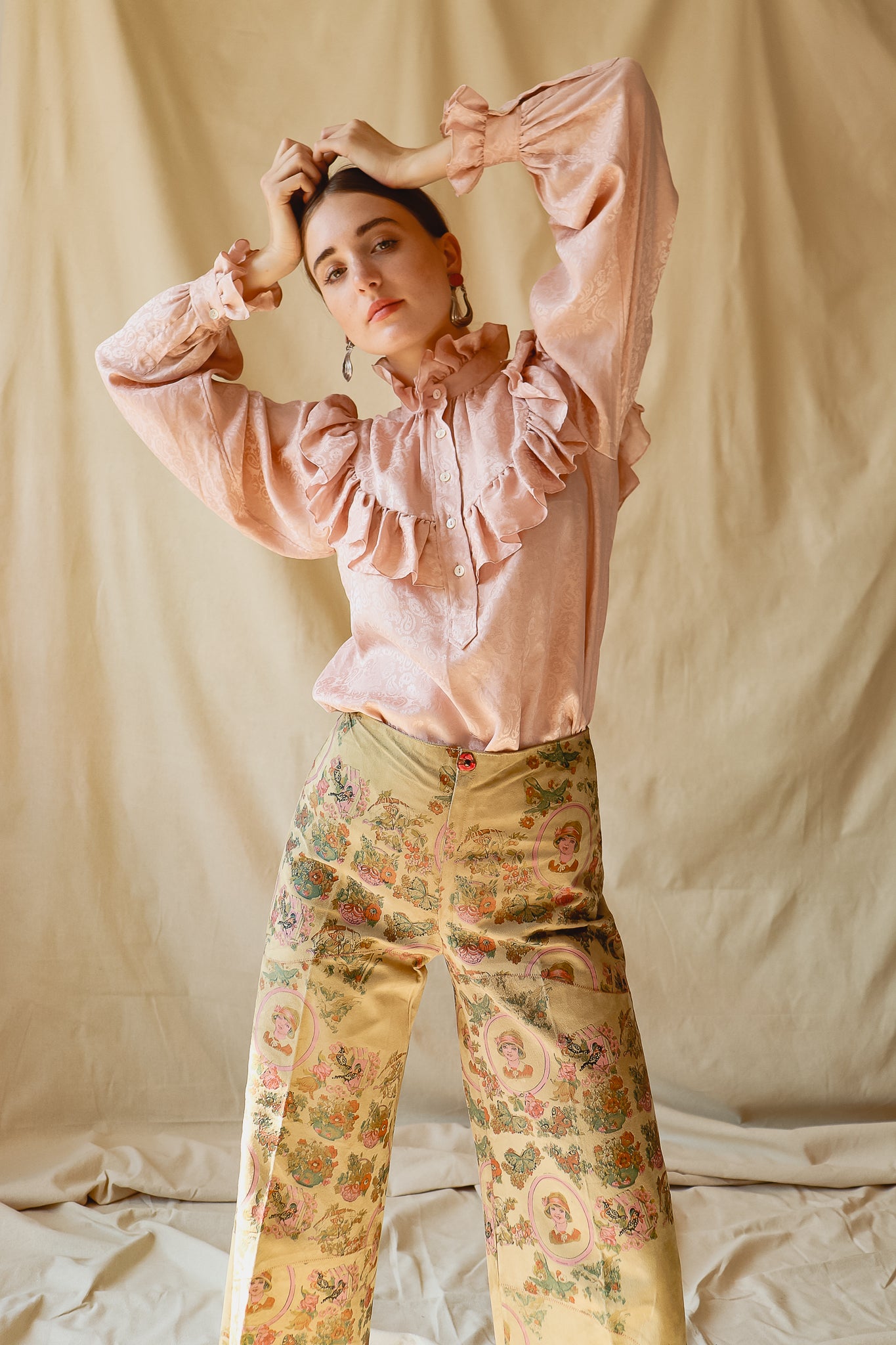 Recess Vintage Consignment LA Girl w/ hands on head in YSL Blouse & Painted Suede Pants