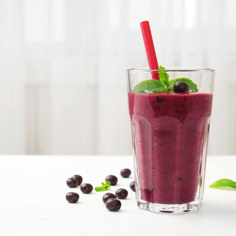 Berry Bliss Smoothie in Glass with blueberries scattered on table
