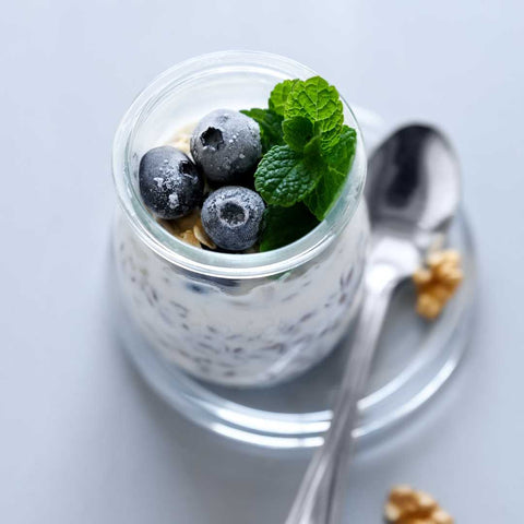Overnight Chia and Muesli Pudding in a glass jar topped with blueberry and mint