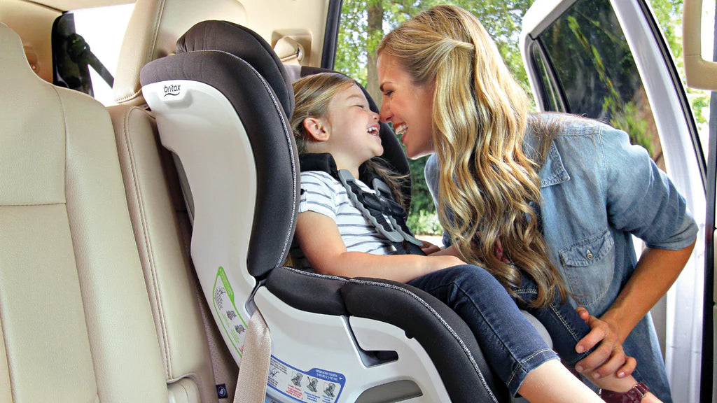a mother laughing with her baby in a convertible car seat