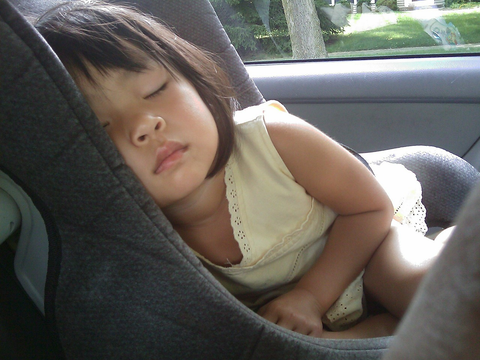 A toddler sleeping in her car seat.