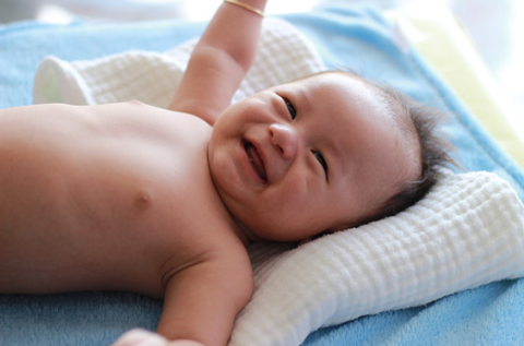 laughing baby laying against a blue blanket