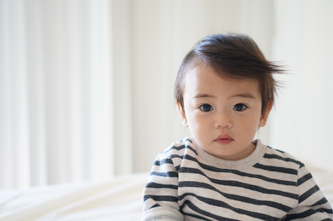 a baby in a black and white striped shirt in a white roo