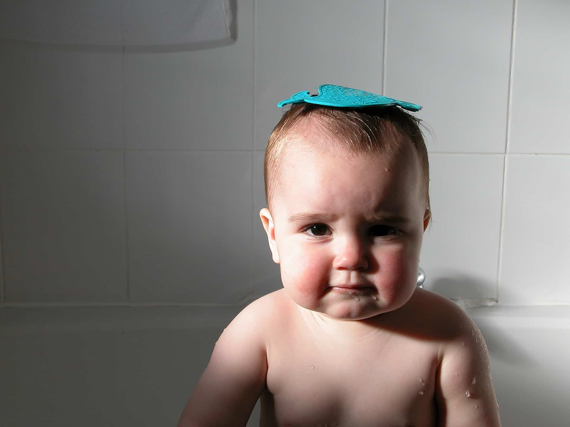 Baby in bath with toy on his head