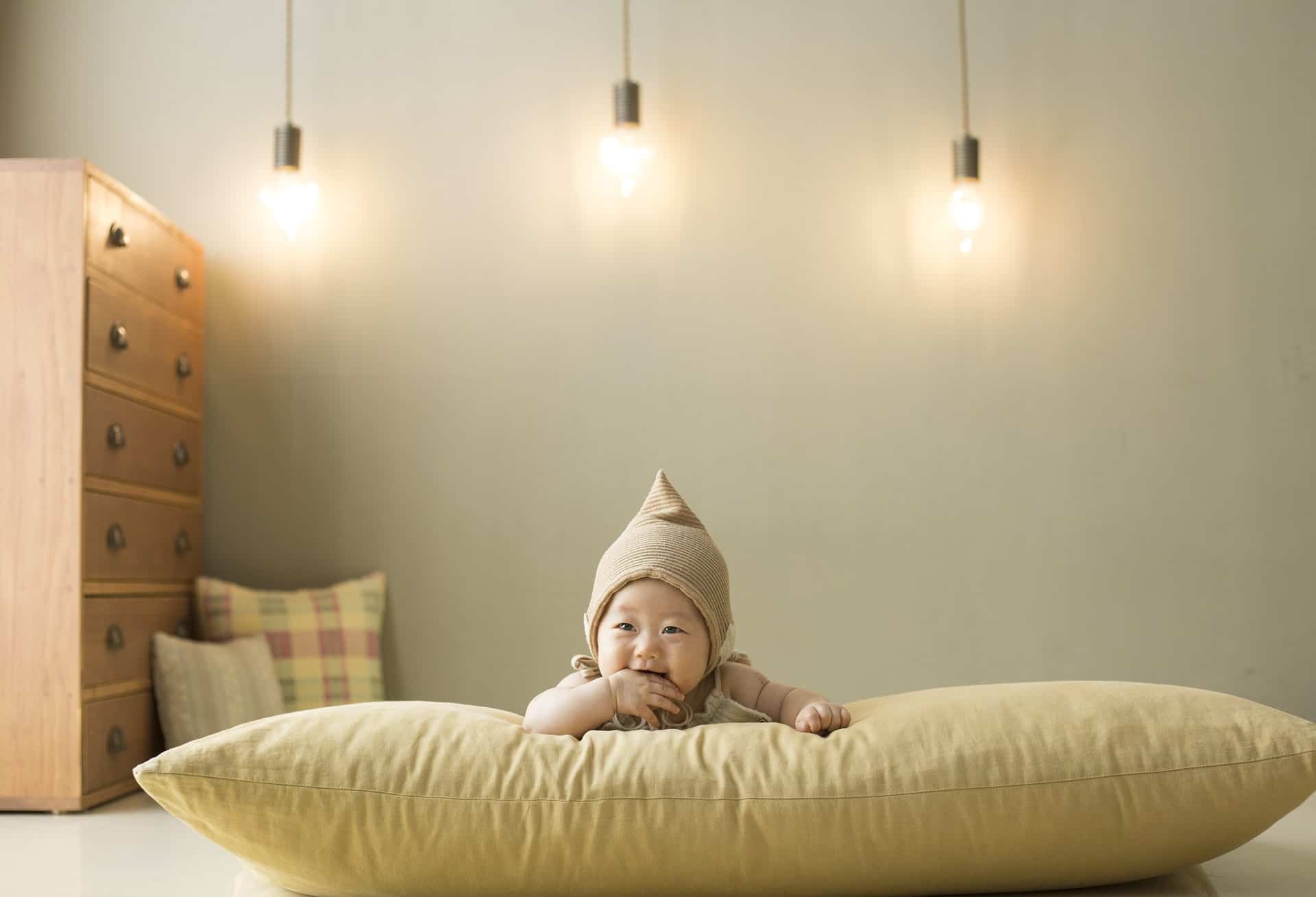 Toddler with a hat lying on a large pillow