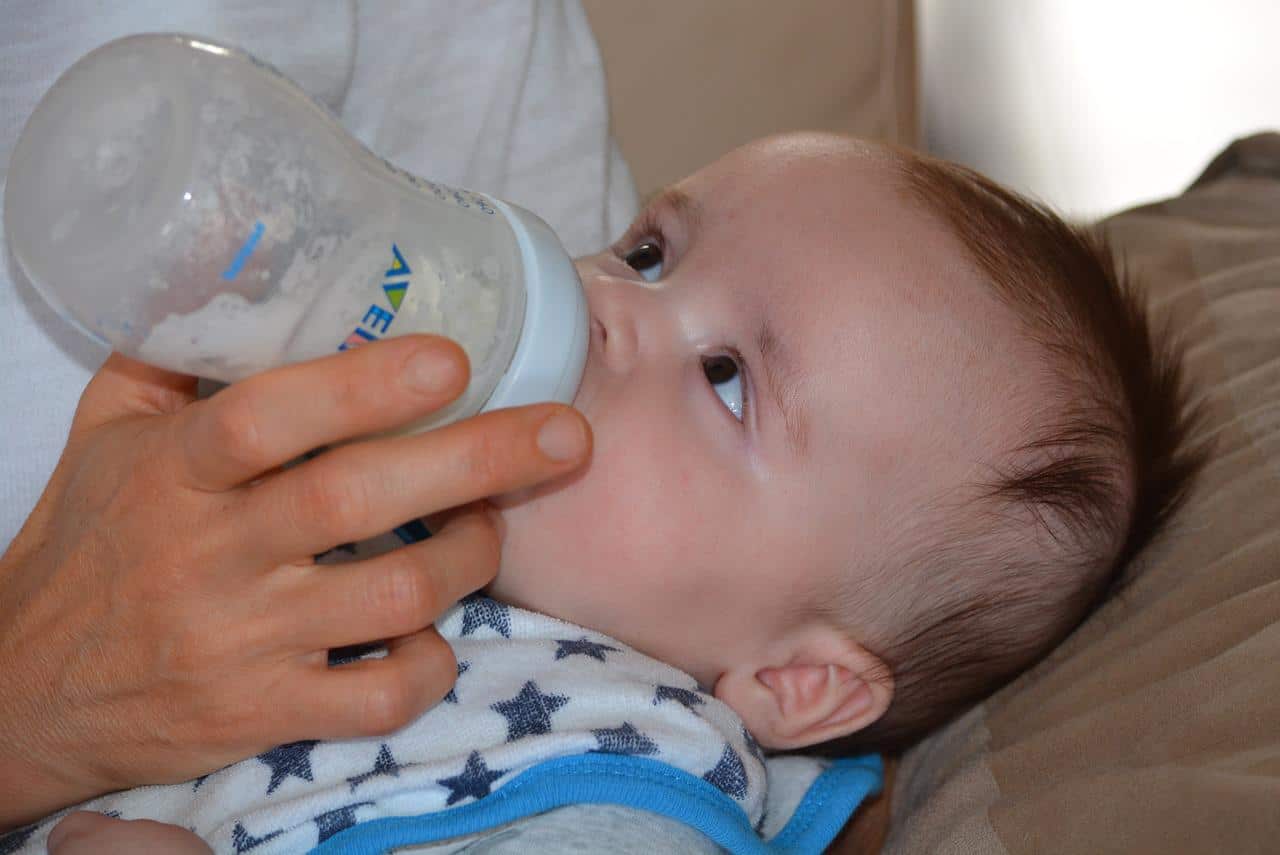a parent feeding their baby with a bottle of formula