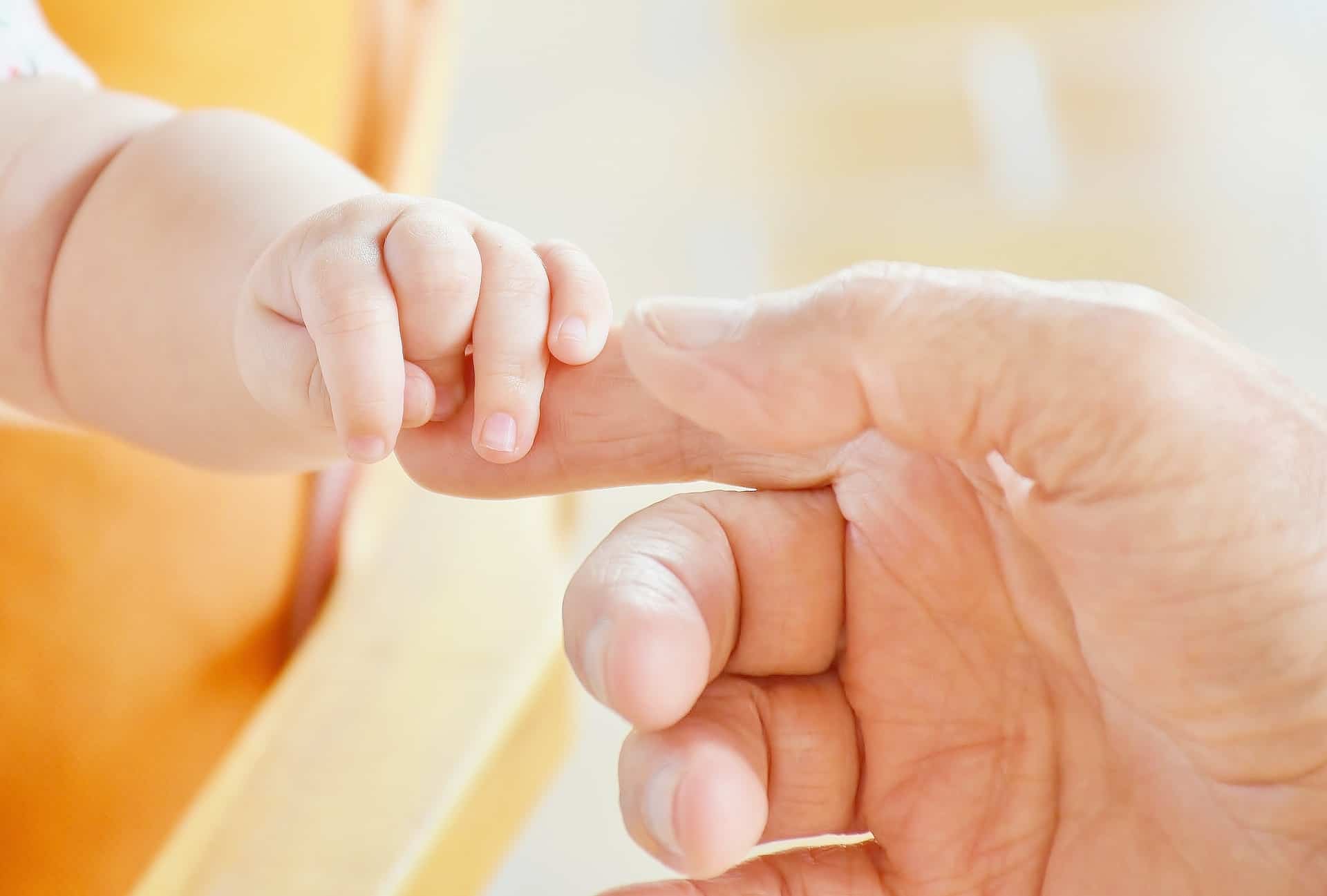 Parent holding a baby’s hand