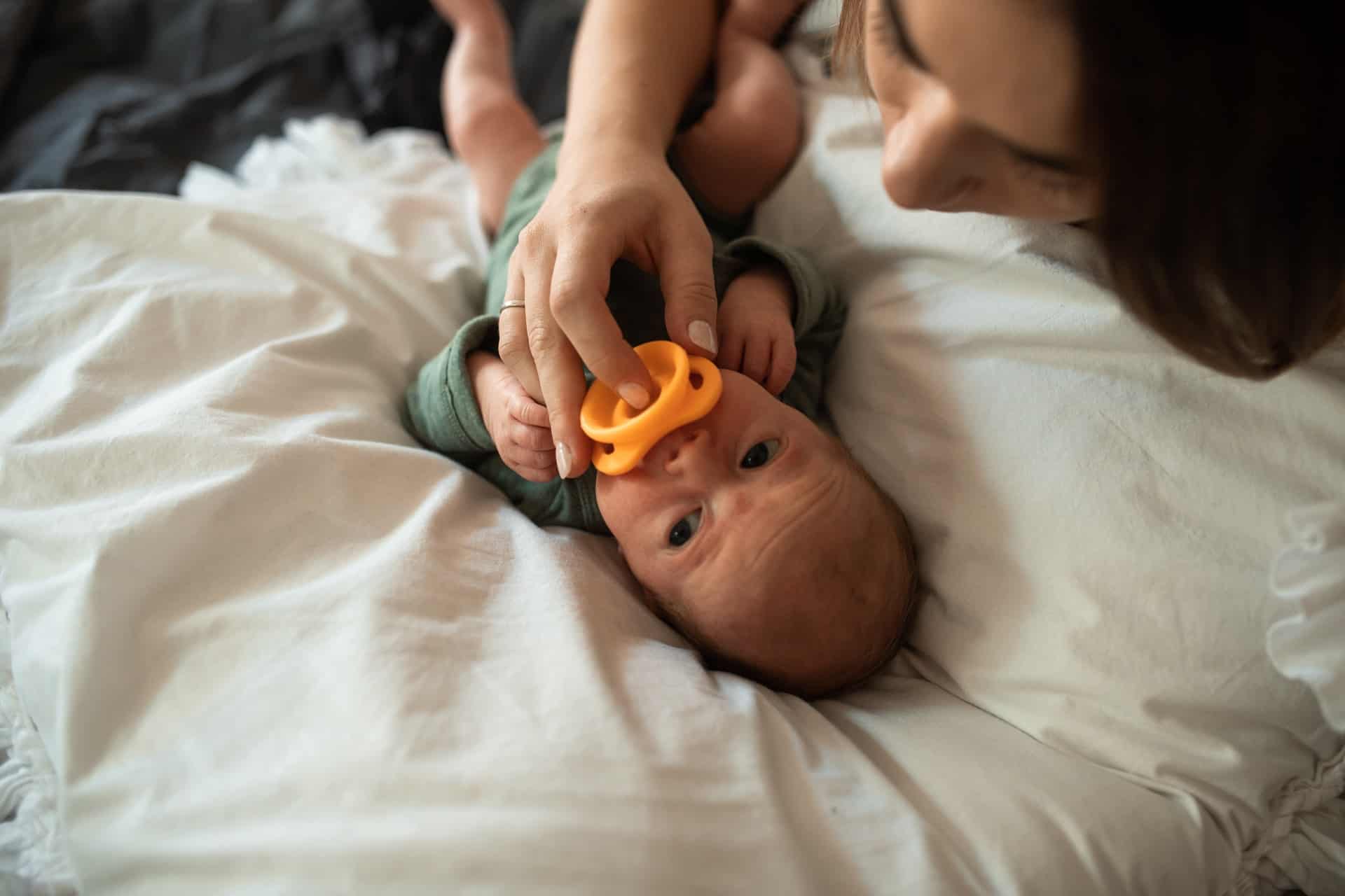 mother helping newborn with pacifier