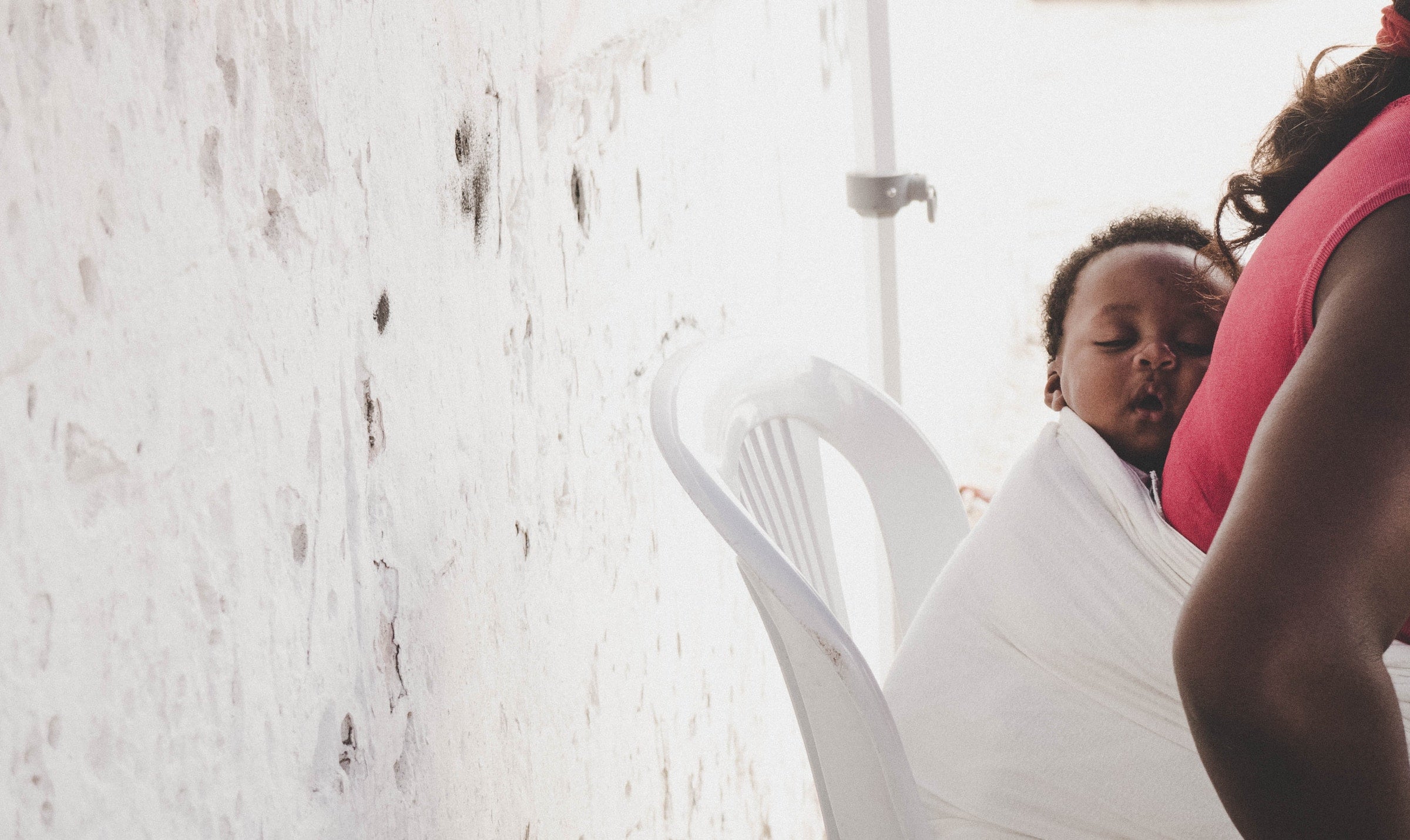 woman using baby wrap to hold a sleeping baby