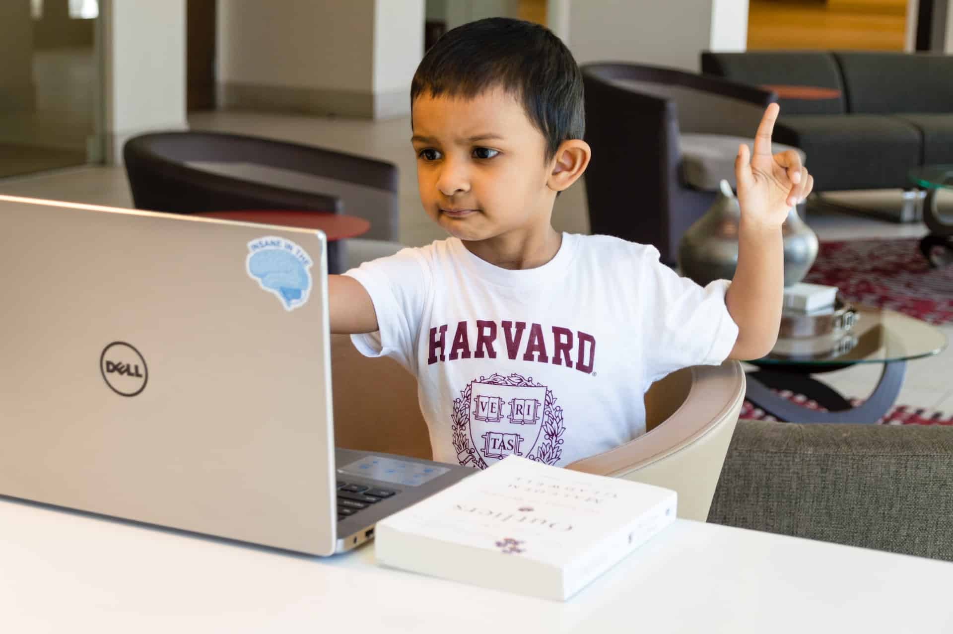 child holding up finger in front of laptop