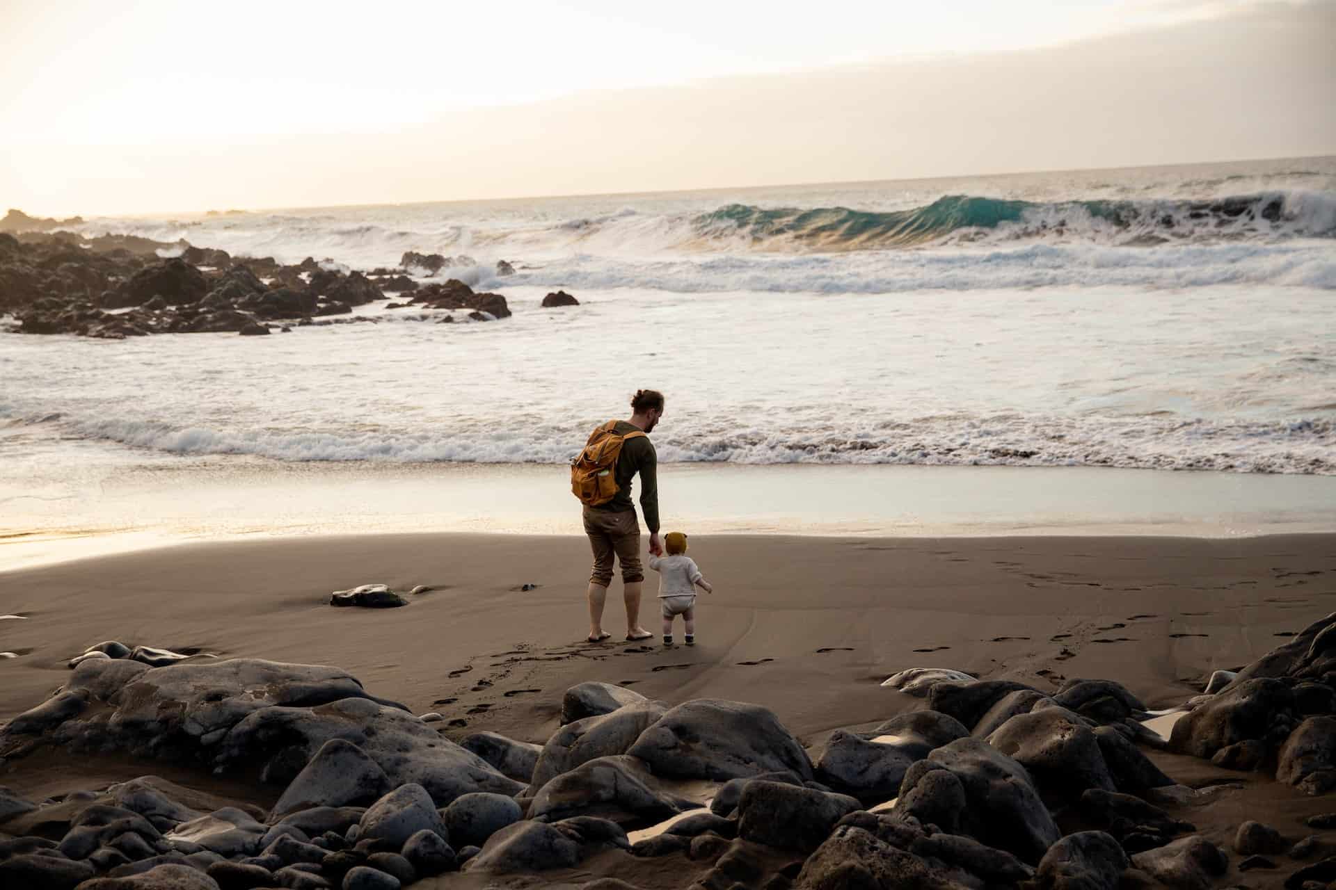 father walking on beach with baby