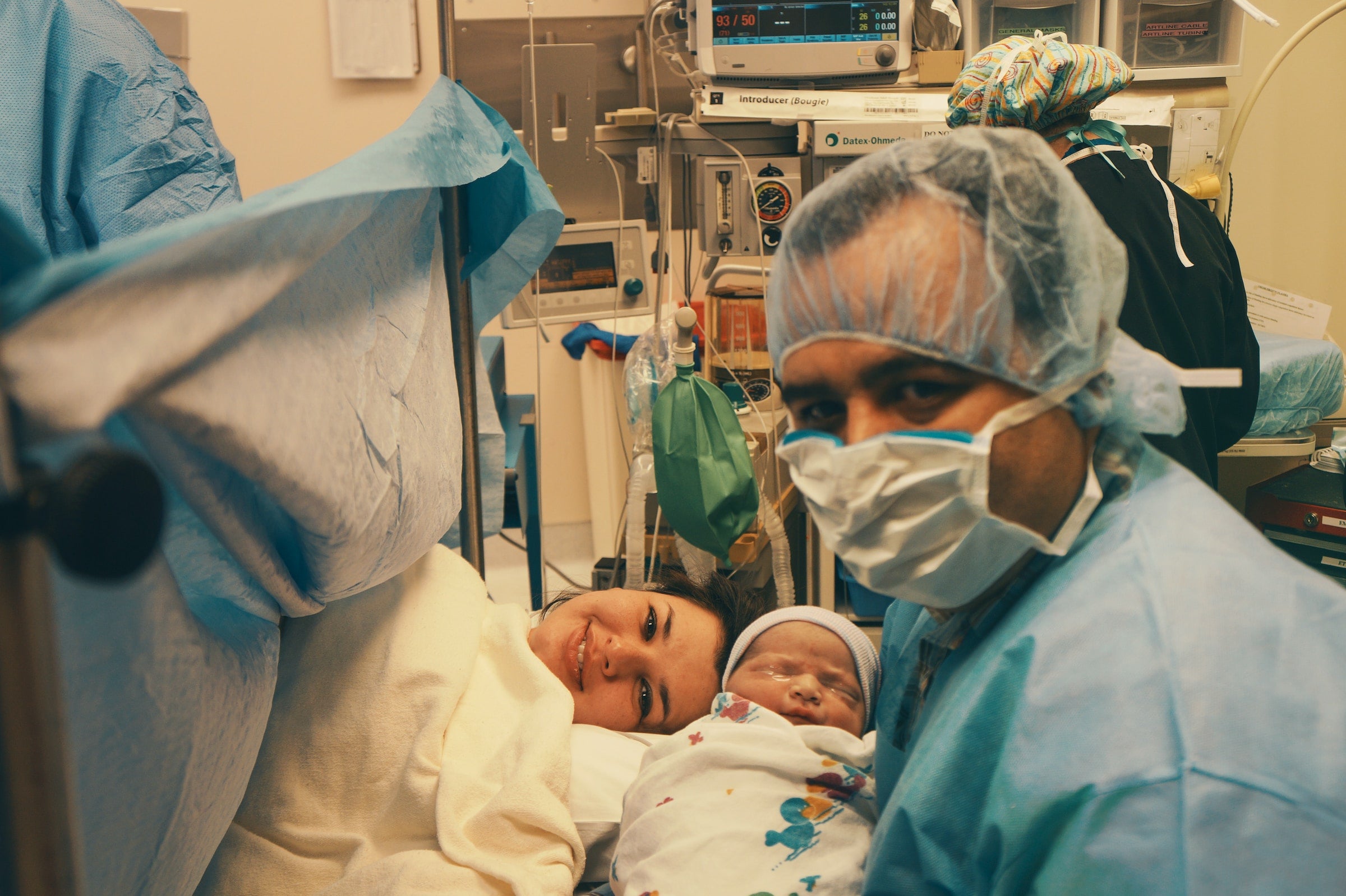 pregnant woman who just gave birth smiling with baby and doctor