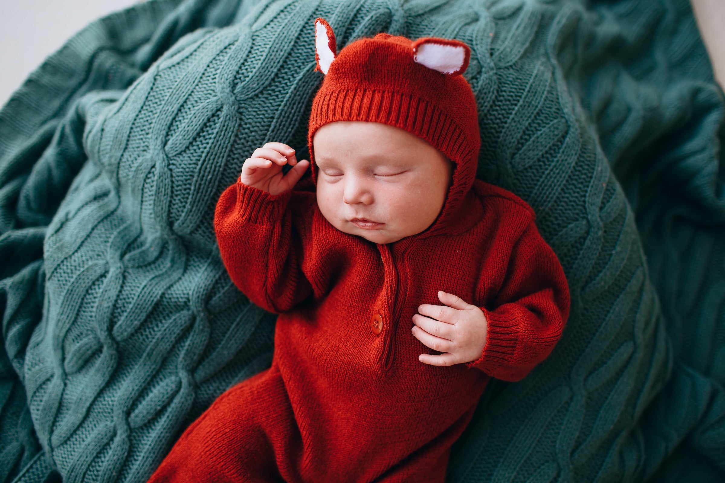 a baby sleeping while wearing a teddy bear onesie