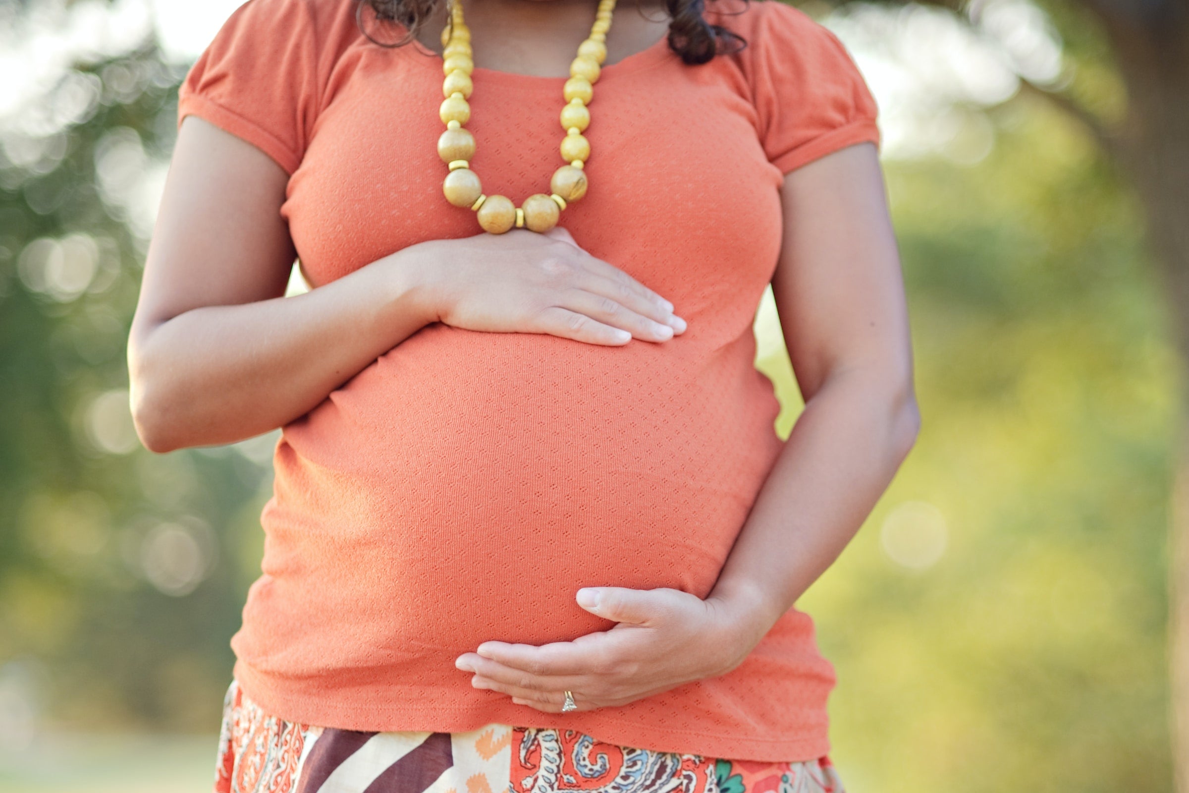 Pregnant woman holding belly outside