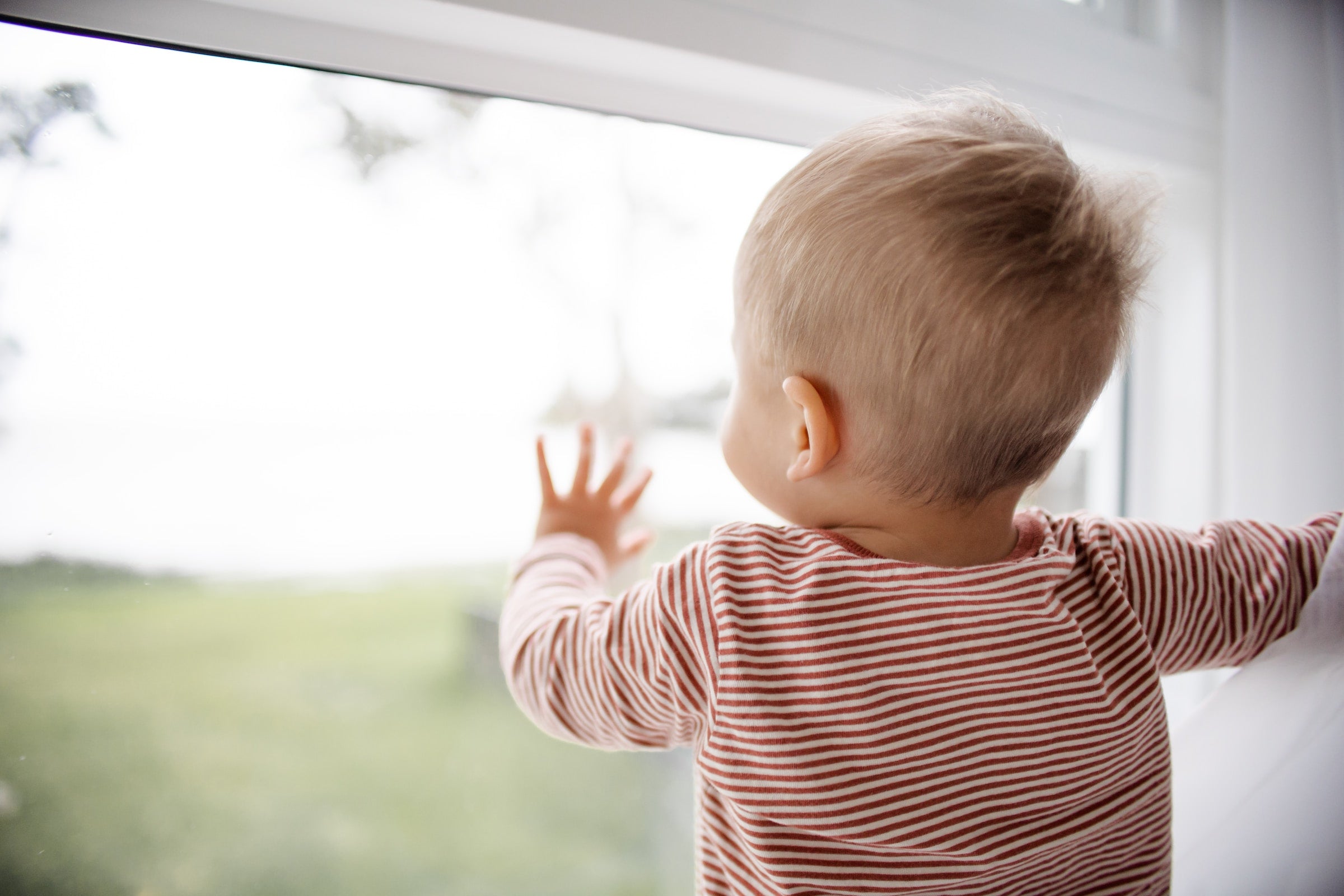 6 month old baby looking out of a window