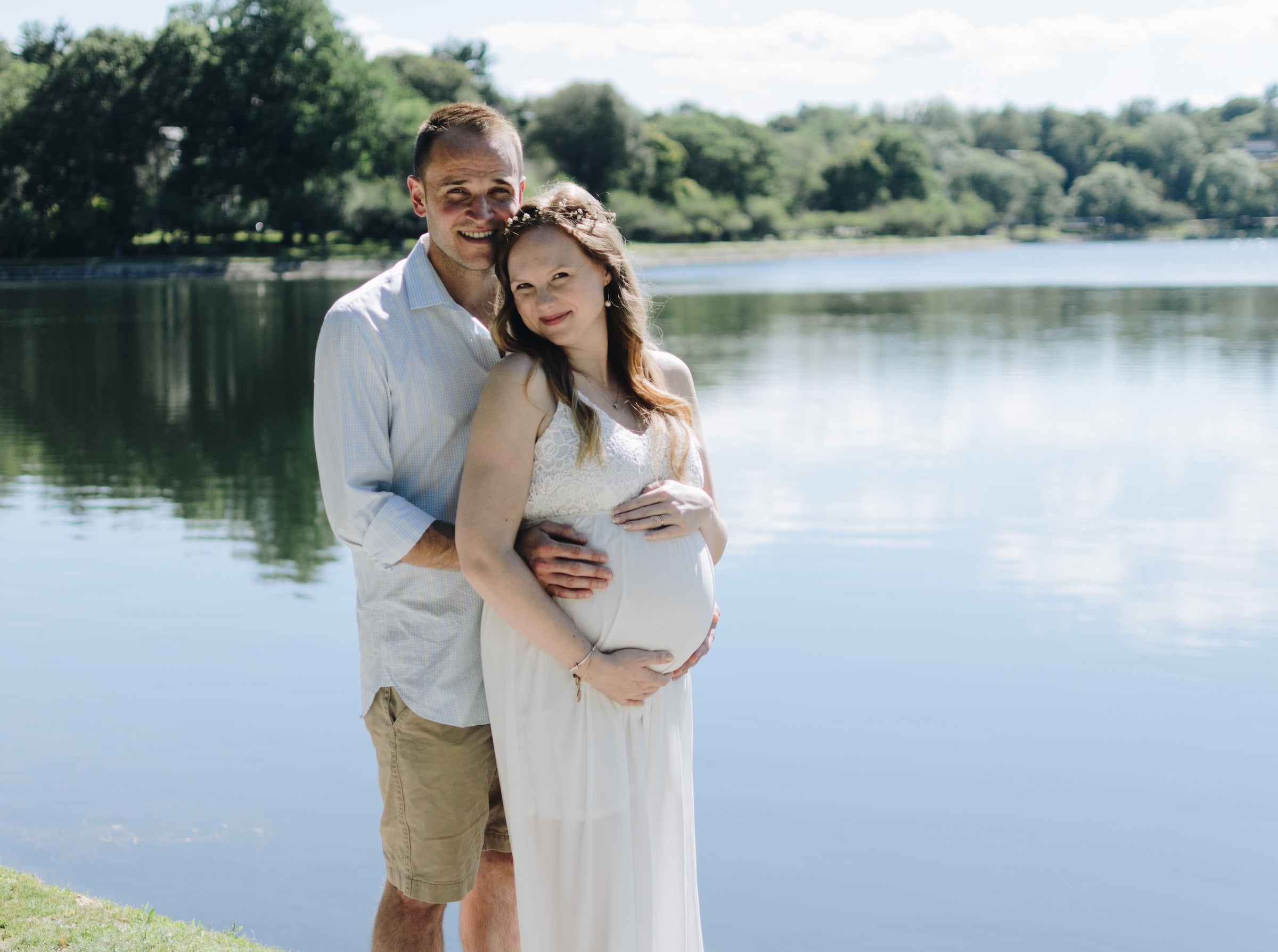 pregnant woman and man posing in front of a lake