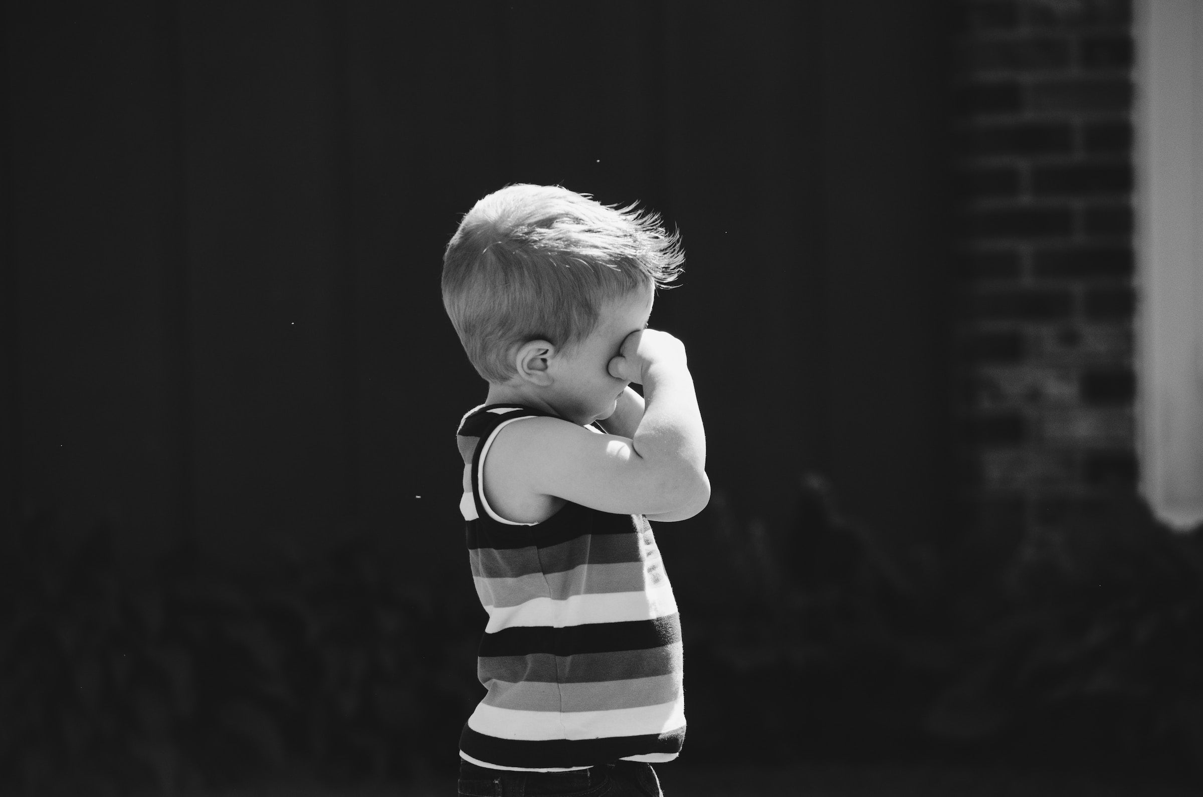 a young boy rubbing his eyes due to allergies