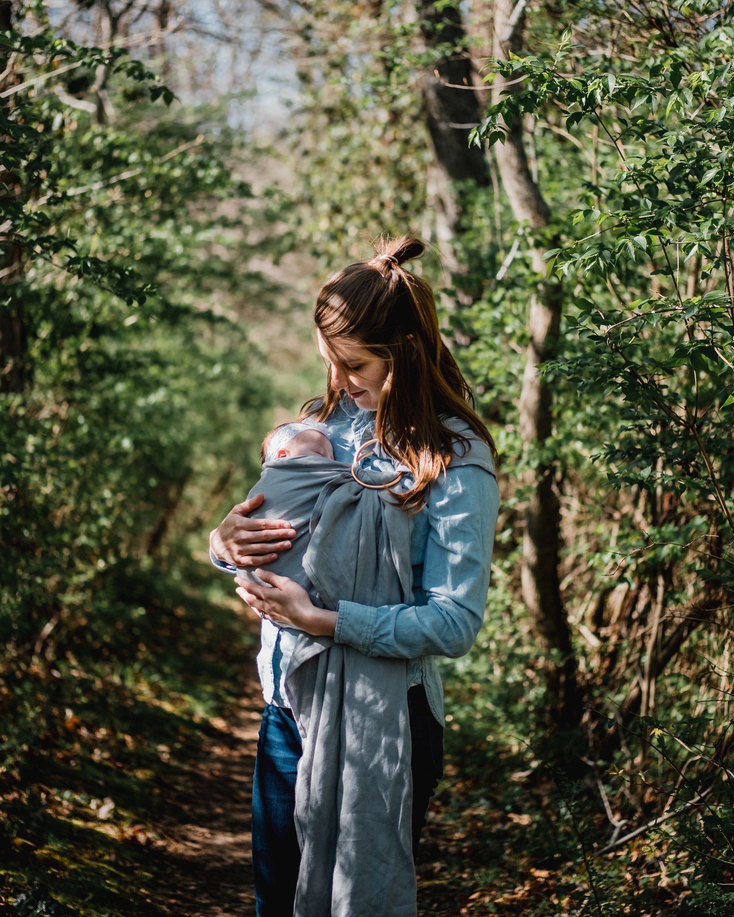 woman holding a baby with a baby wrap in nature