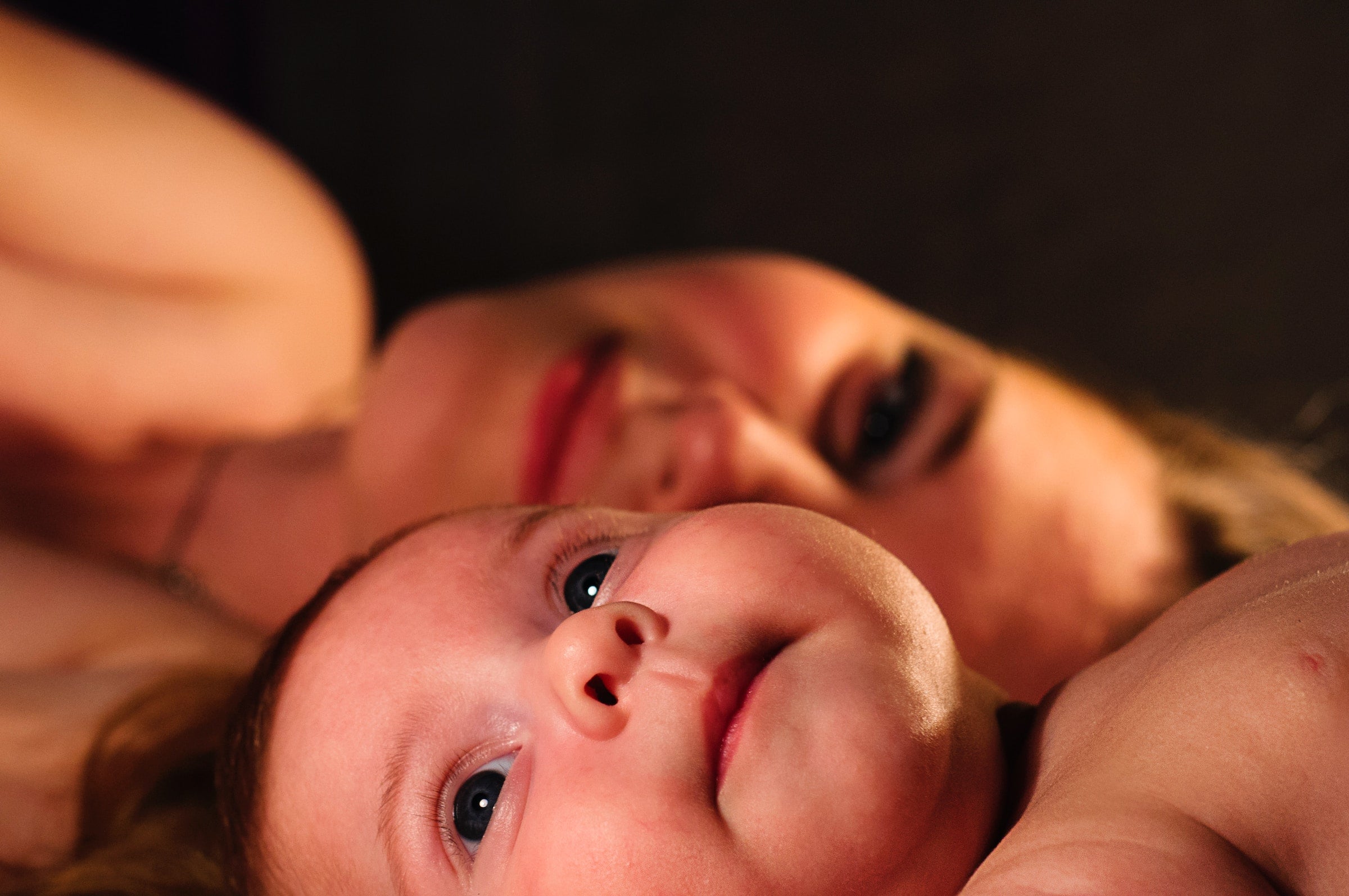 baby and mother laying in a bed