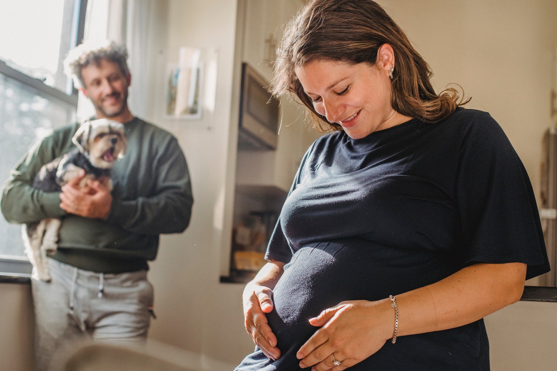 happy pregnant woman holding her stomach next to husband