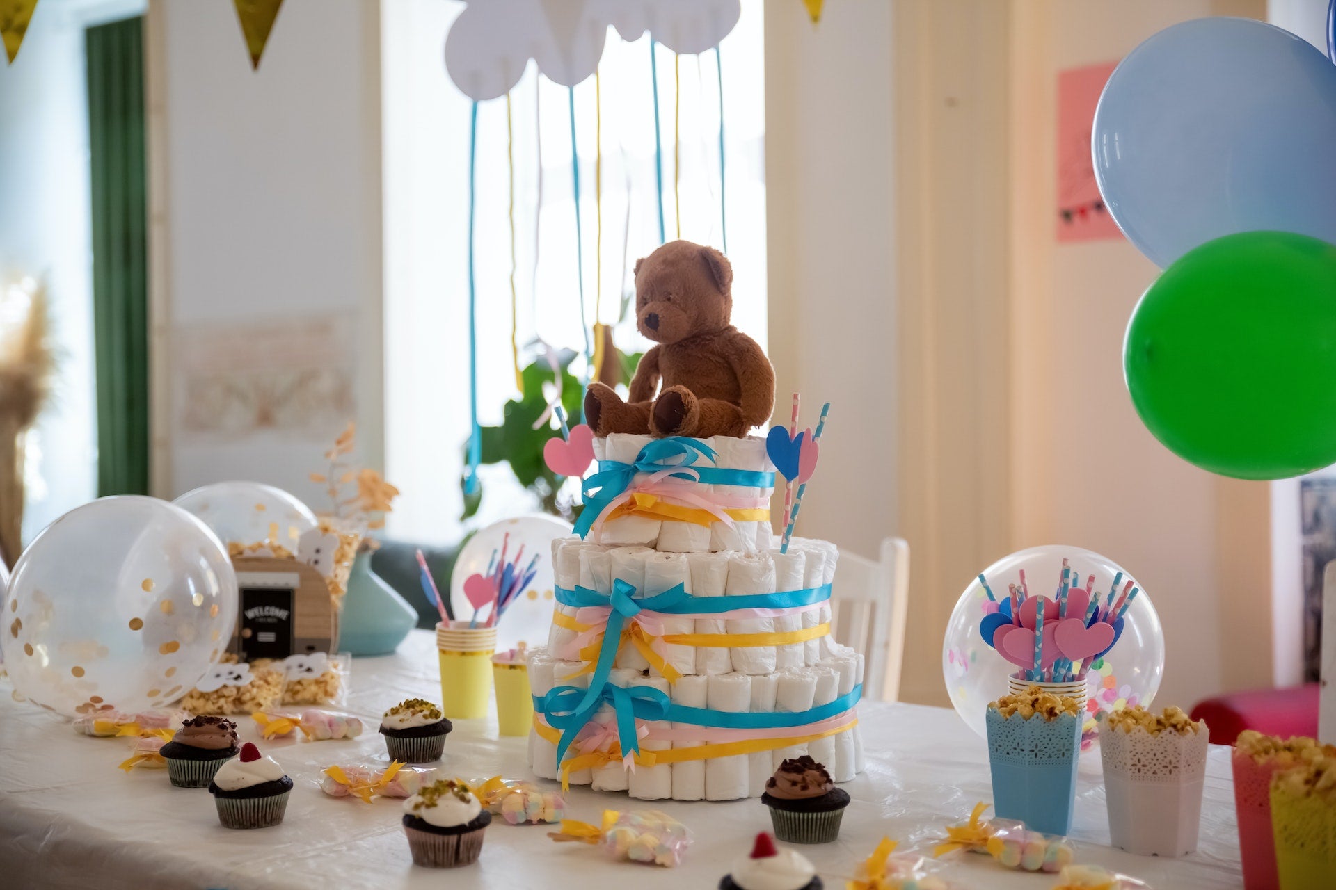 A table with a blue and gold theme, covered with desserts, balloons, and a diaper cake
