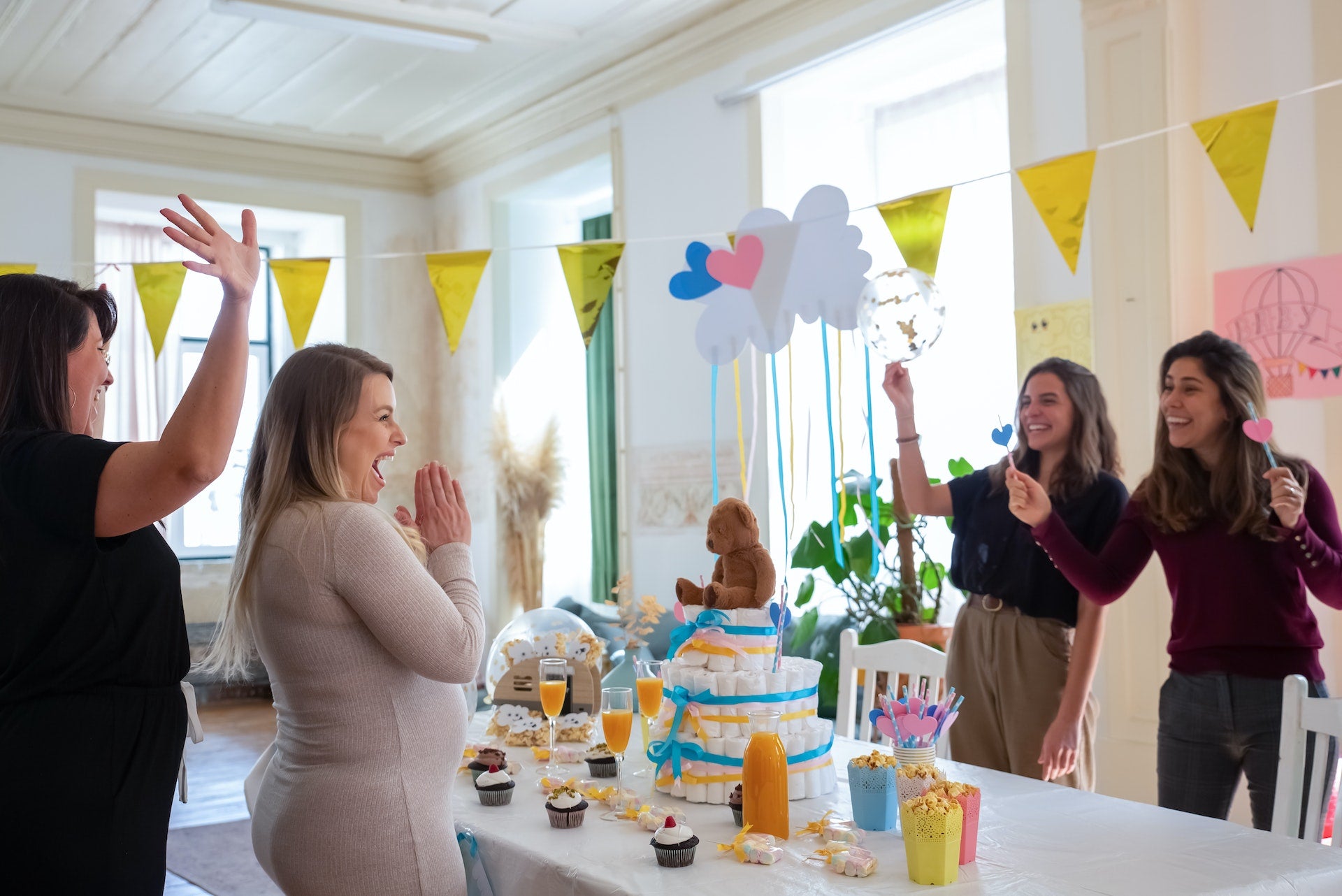 A group of women show excitement around a baby shower decorated table