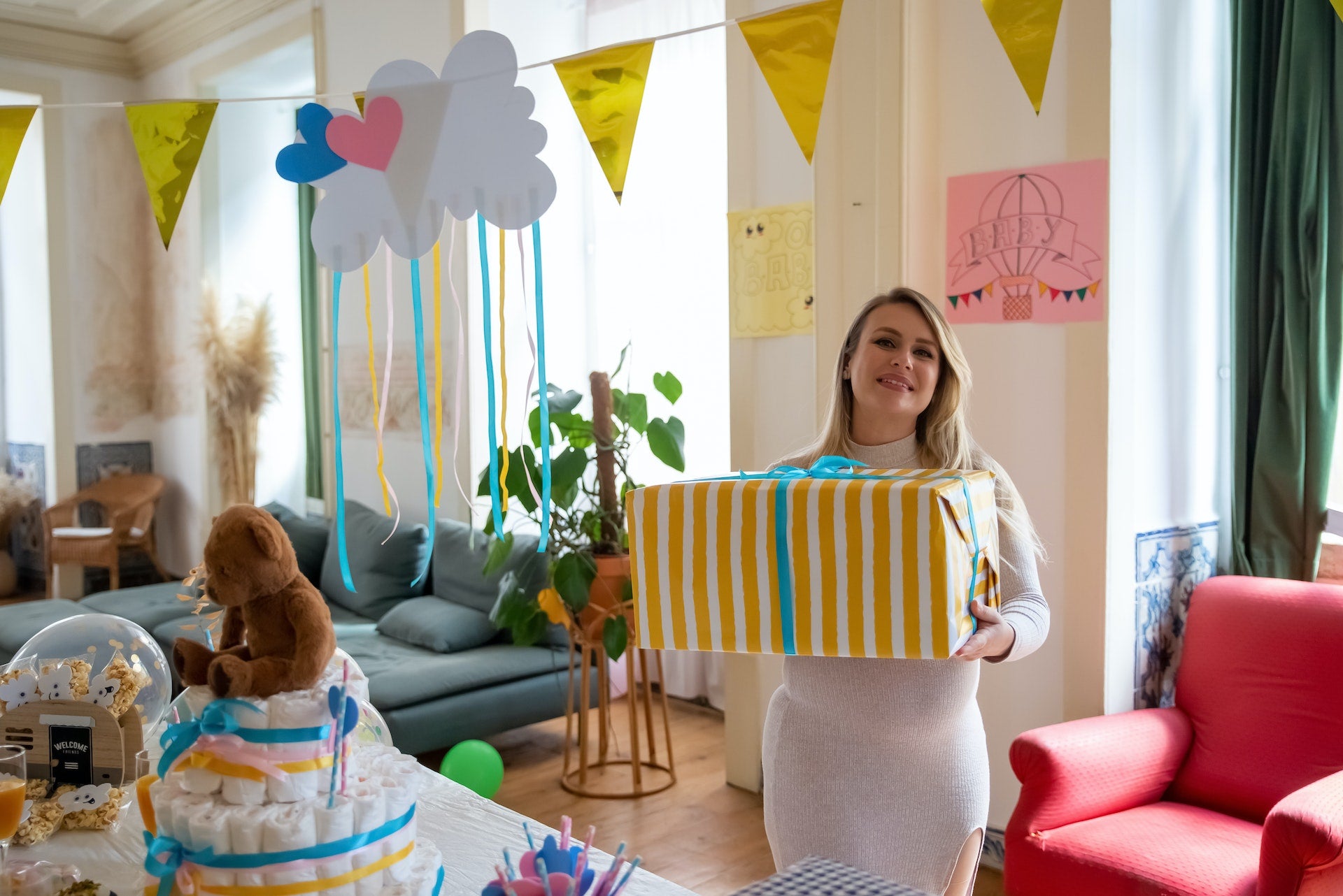 Pregnant woman holds a large present wrapped in colorful paper