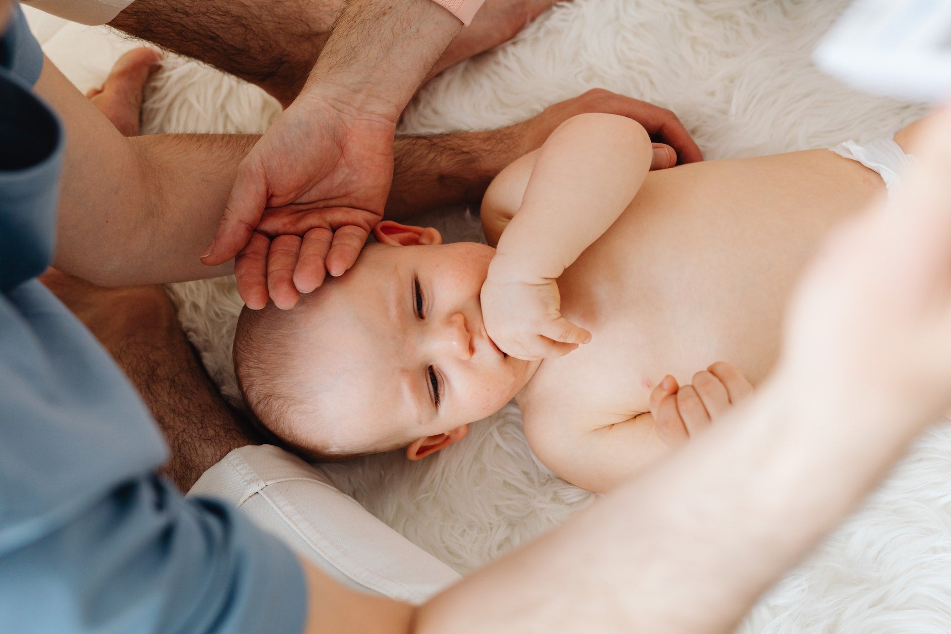 Baby sucking hand with parents