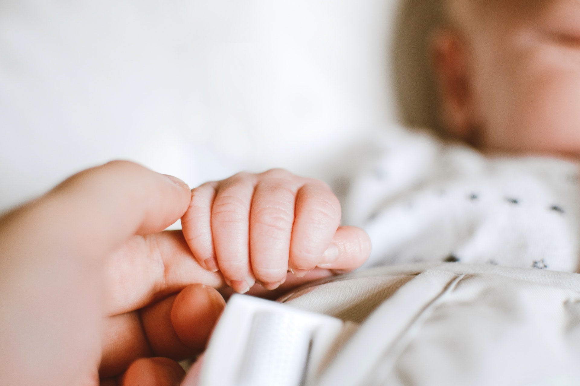 Baby holds persons hand