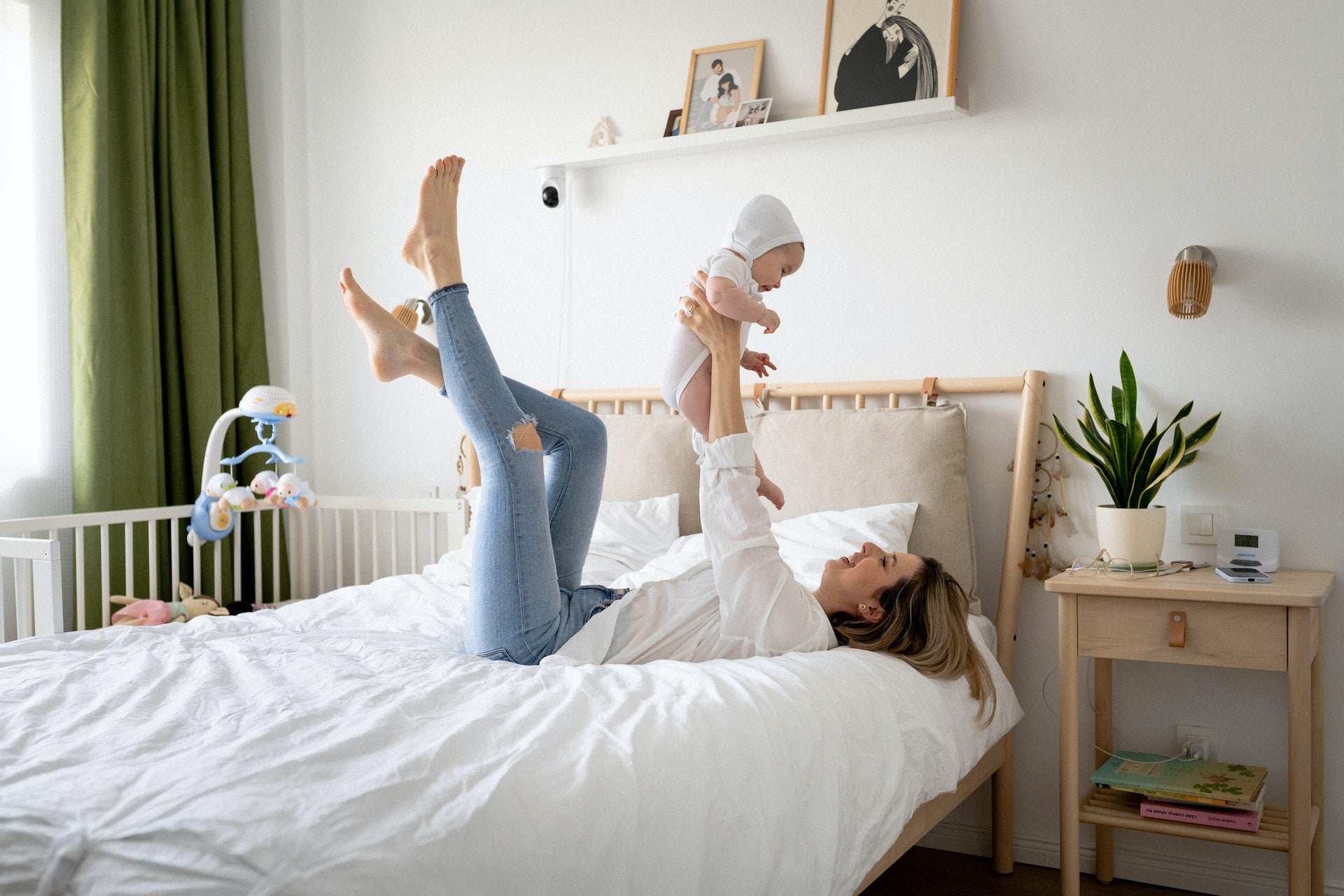 mother holding her newborn baby up while laying in bed