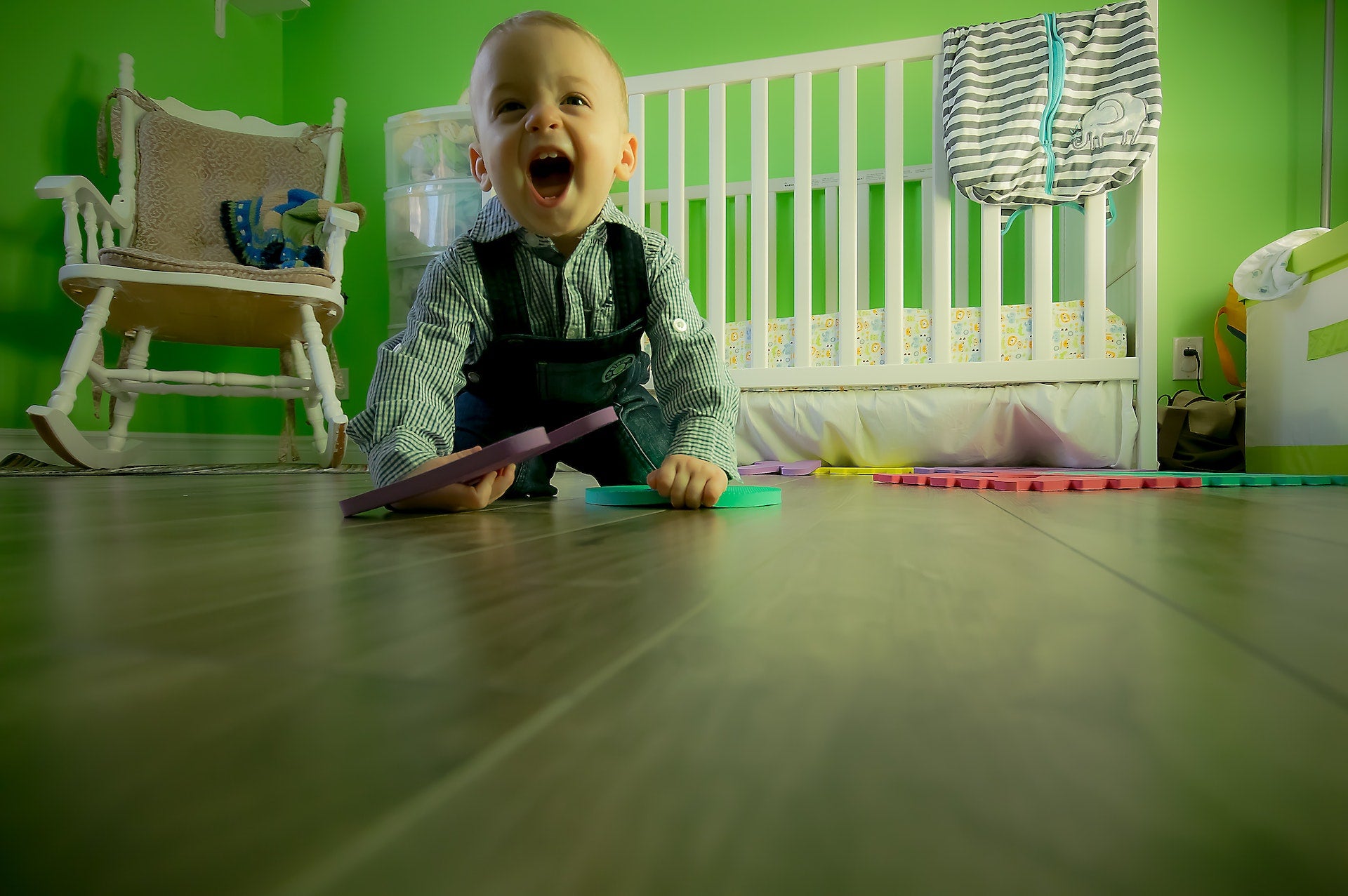 toddler playing in a green bedroom