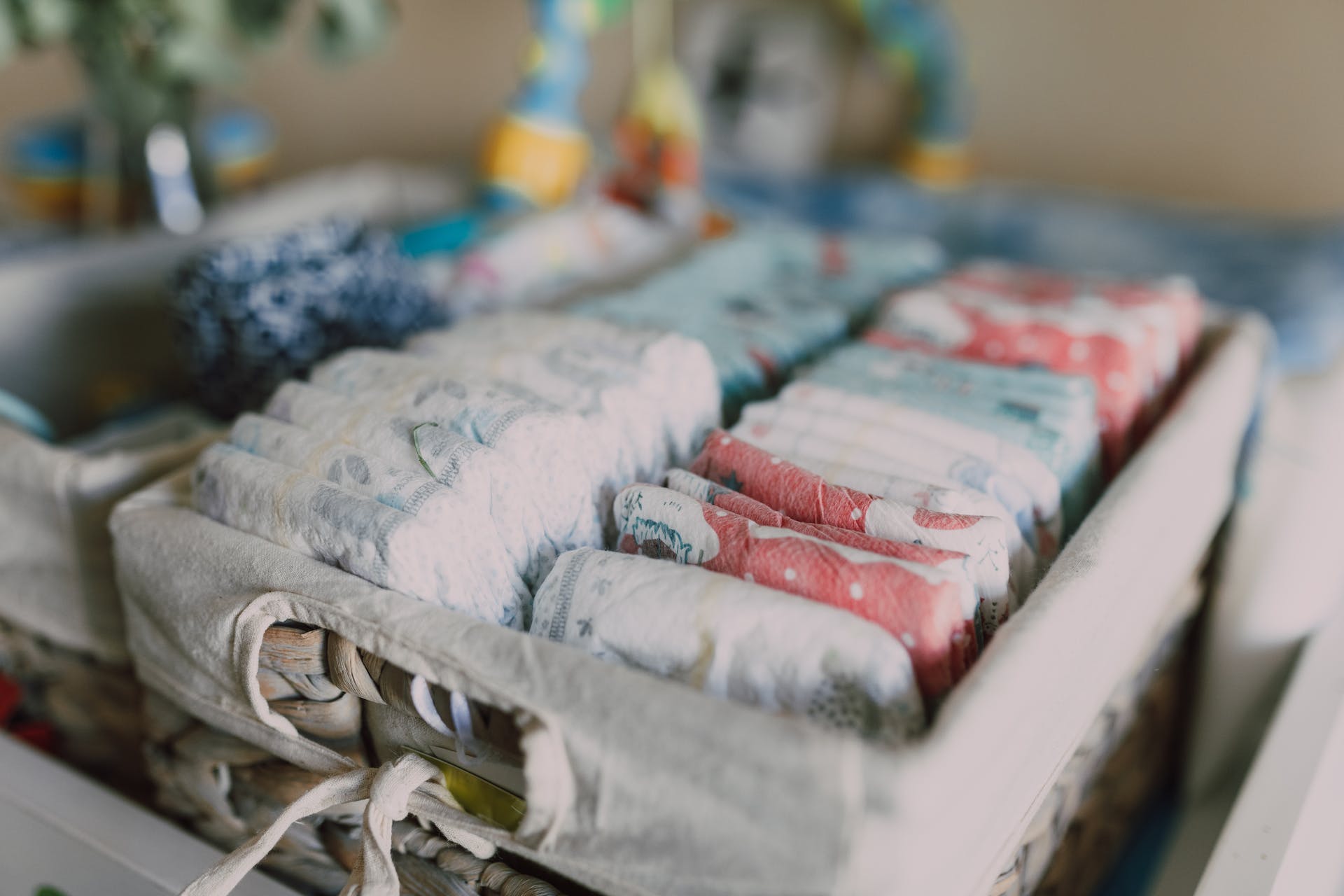 A woven basket holds a stack of colorful diapers