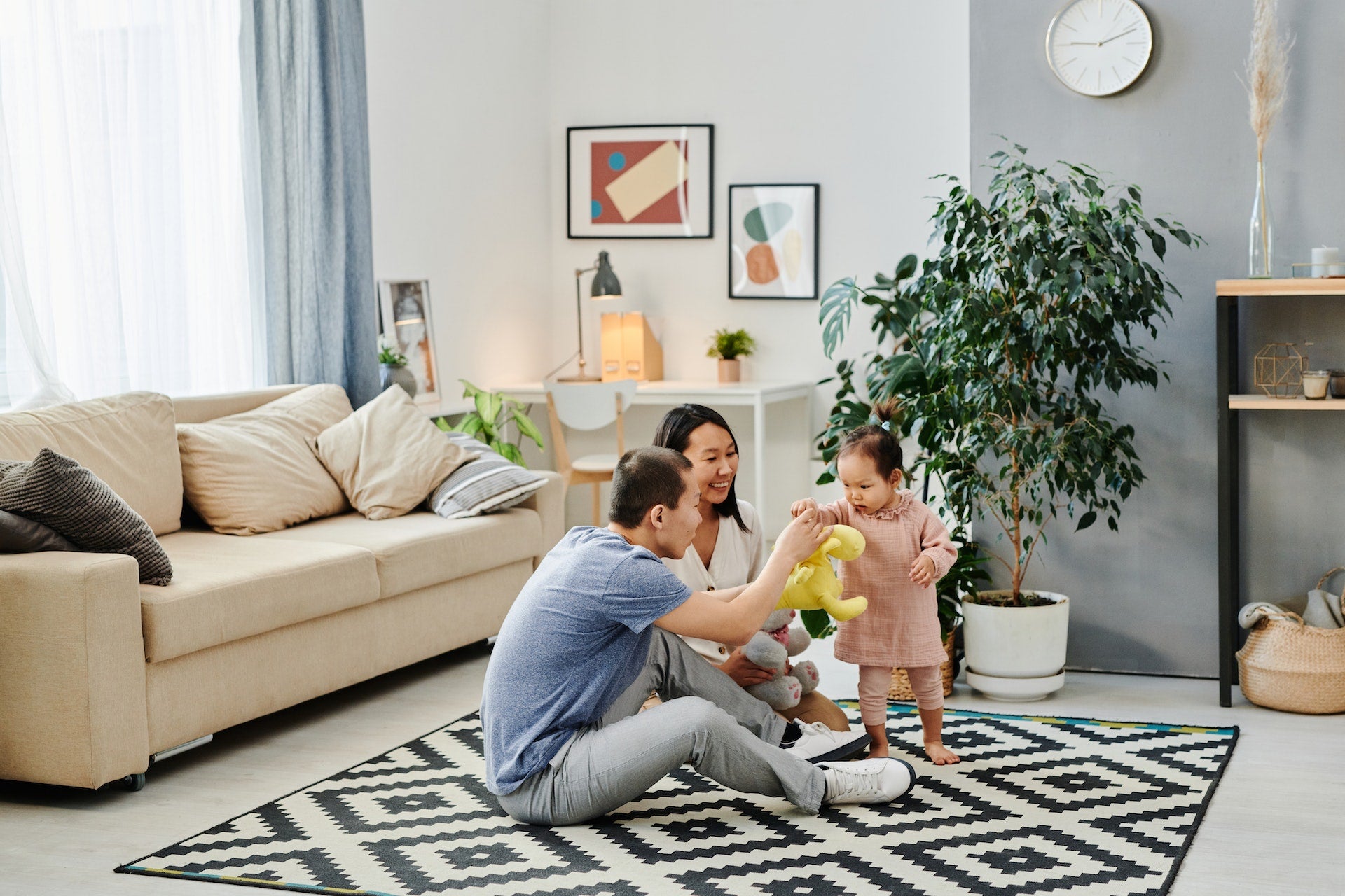 A mother and father play with their toddler on the living room floor
