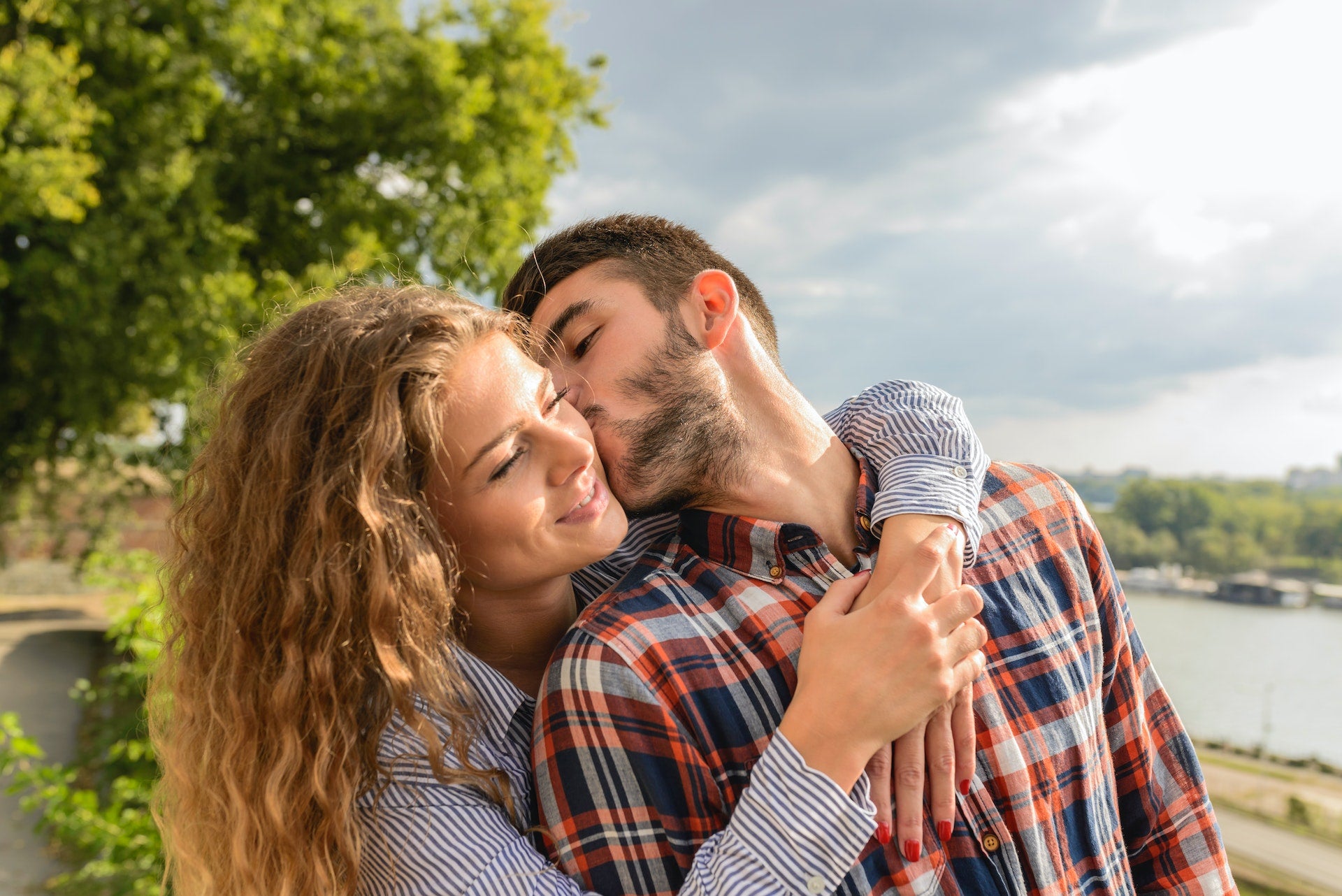 man kissing woman on the cheek while she holds him
