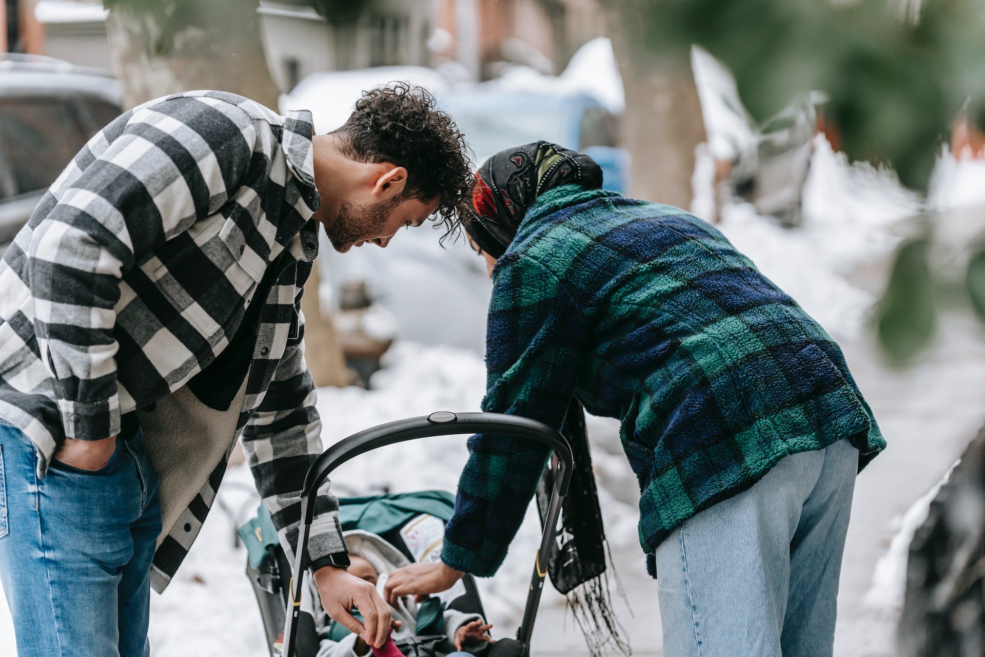 A couple over looks their baby in a stroller during a snowy day