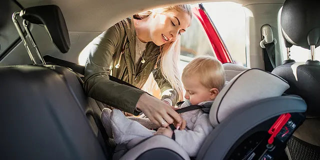 Mom putting child in car seat