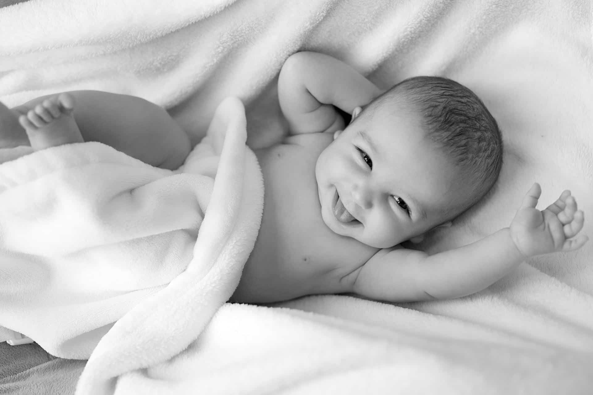 A baby smiling on a blanket