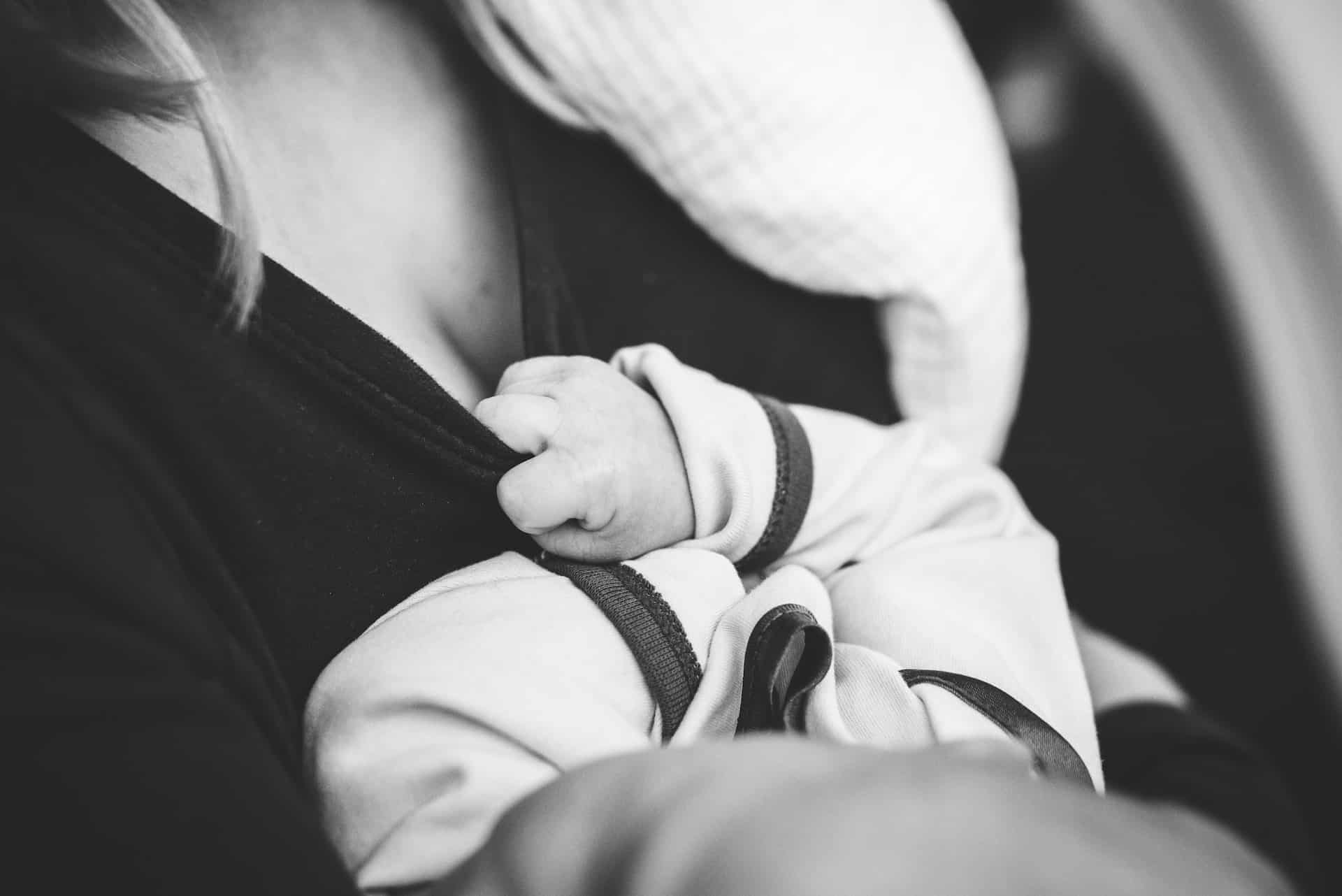 Infant reaching for mother’s breasts